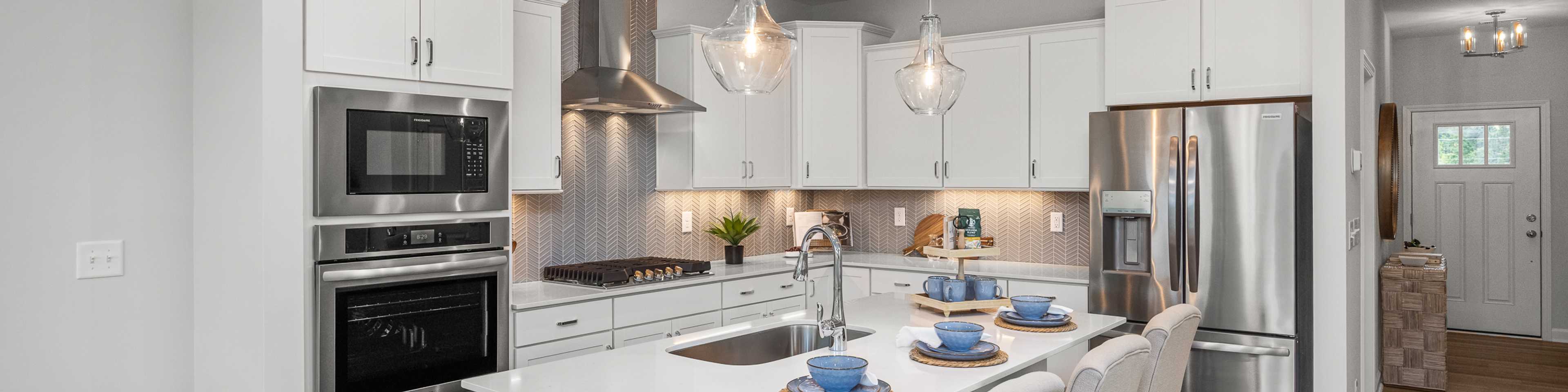 Spacious modern kitchen in Summers Walk Davidson NC with white cabinetry island seating stainless appliances hardwood floors