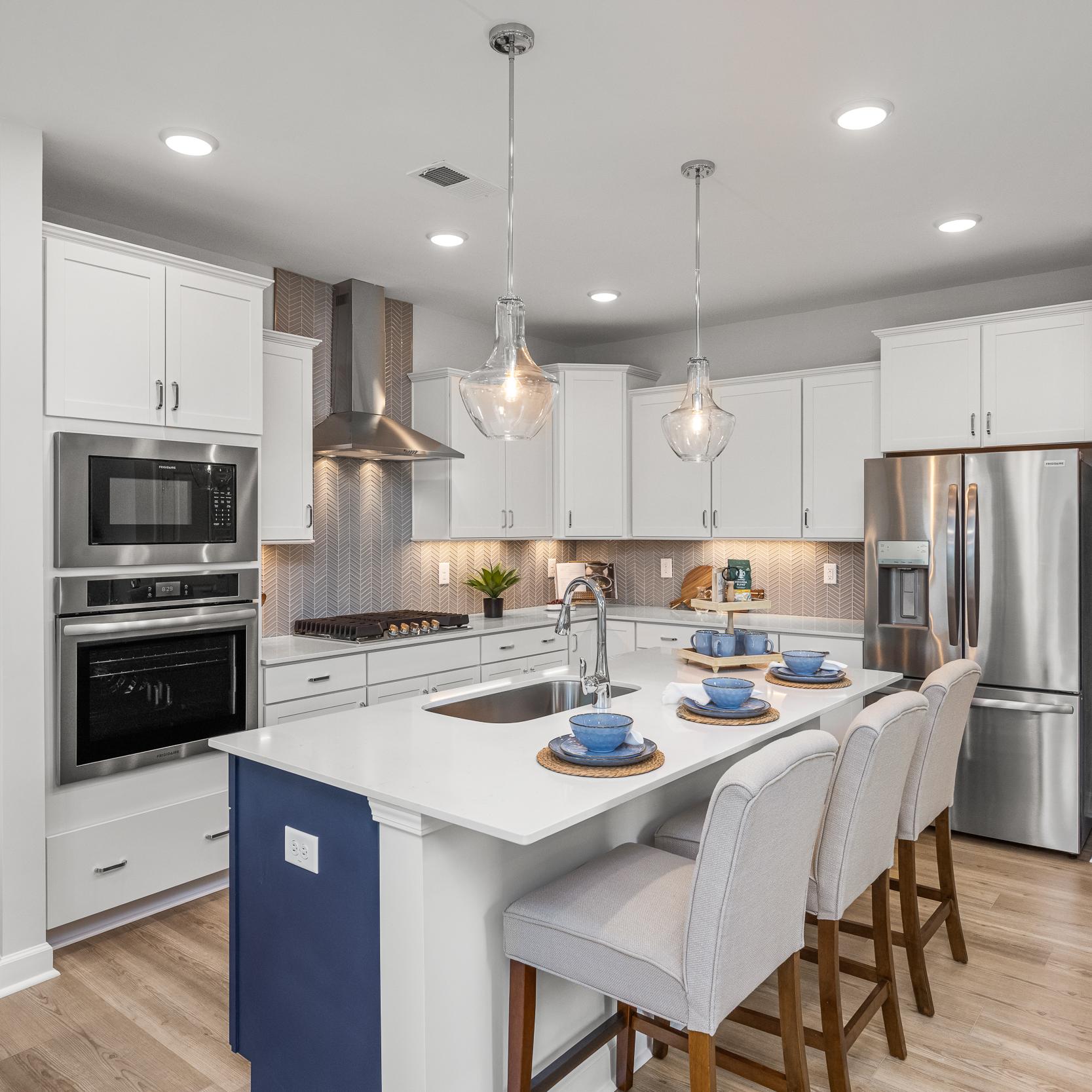 Spacious modern kitchen in Summers Walk Davidson NC with white cabinetry island seating stainless appliances hardwood floors