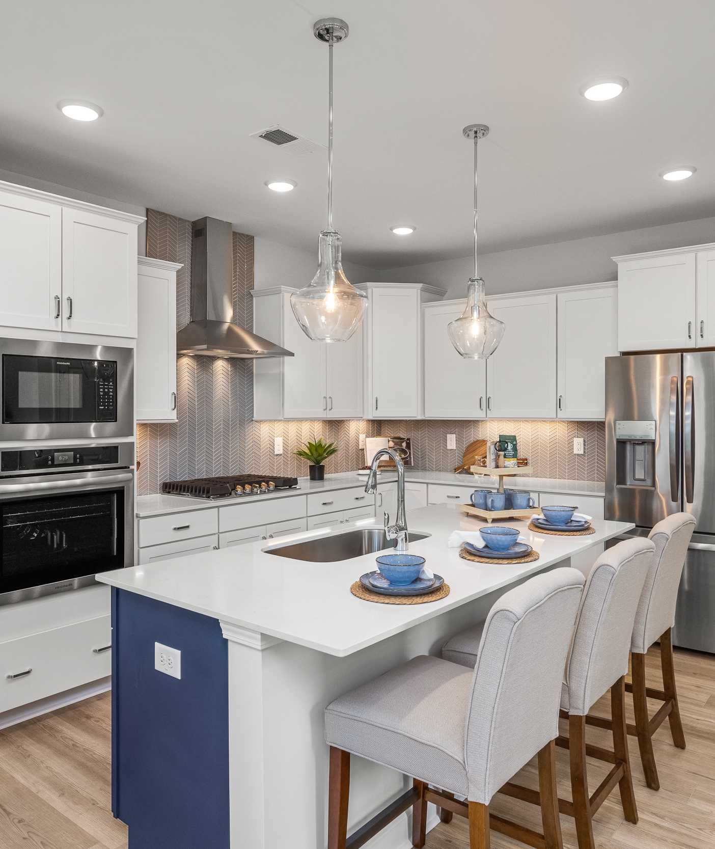 Spacious modern kitchen in Summers Walk Davidson NC with white cabinetry island seating stainless appliances hardwood floors