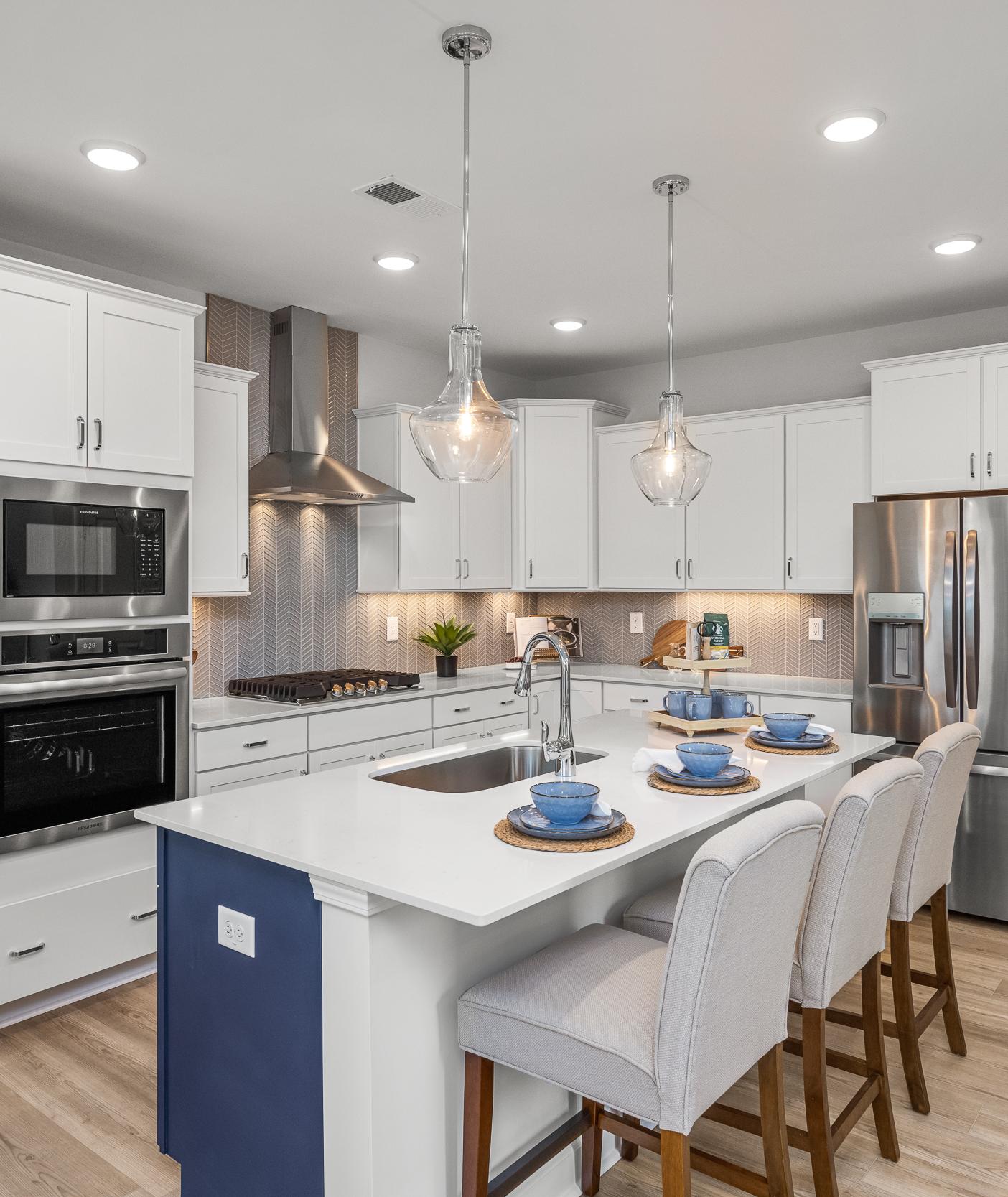 Spacious modern kitchen in Summers Walk Davidson NC with white cabinetry island seating stainless appliances hardwood floors