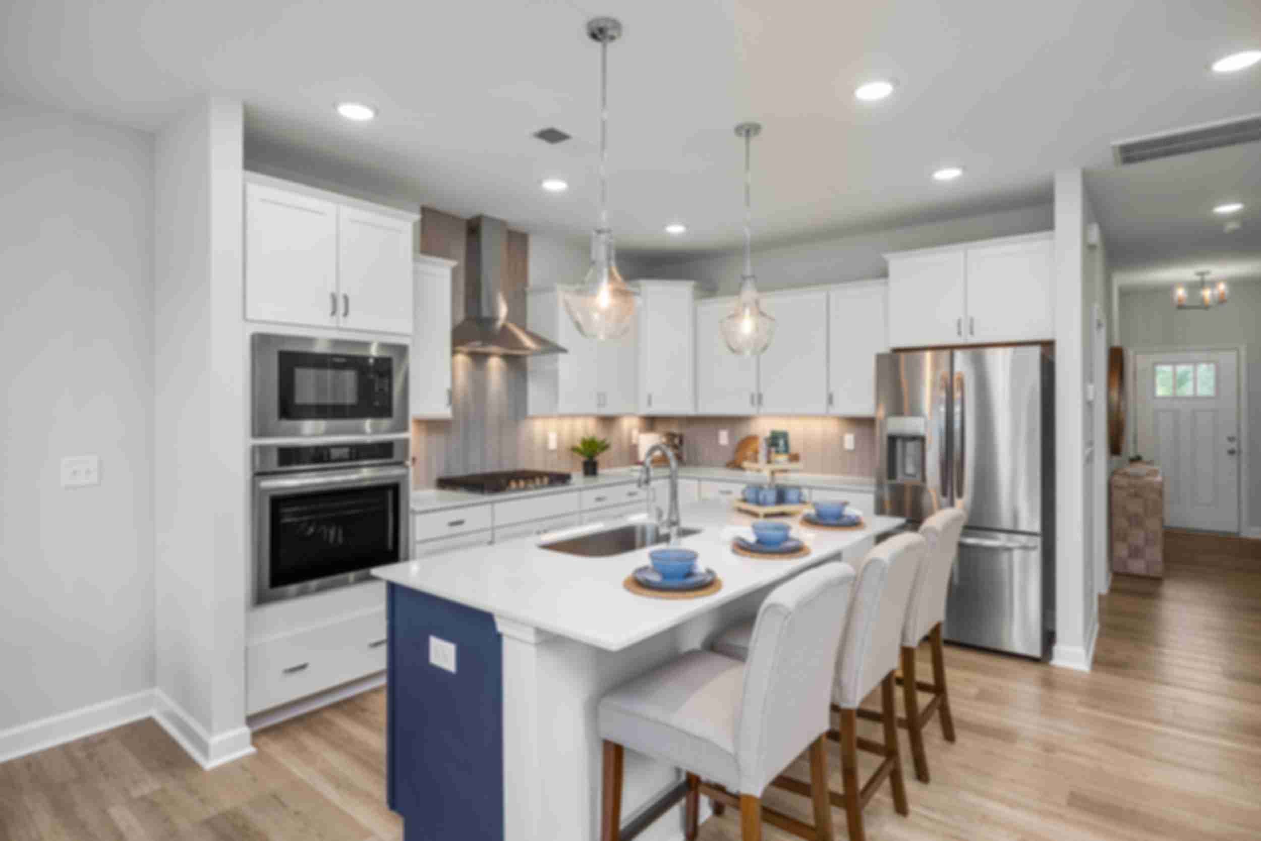 Spacious modern kitchen in Summers Walk Davidson NC with white cabinetry island seating stainless appliances hardwood floors