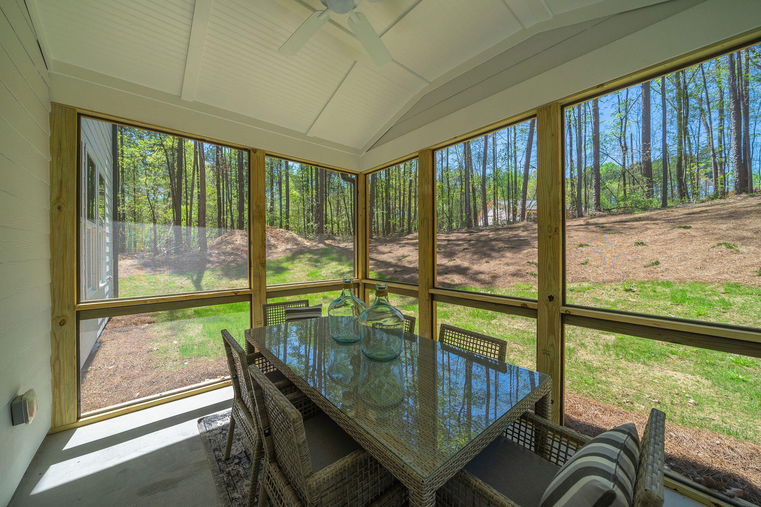 Spacious screened porch at Riverwood in Dallas, Georgia with wicker dining set, ceiling fan, and wooded backyard views