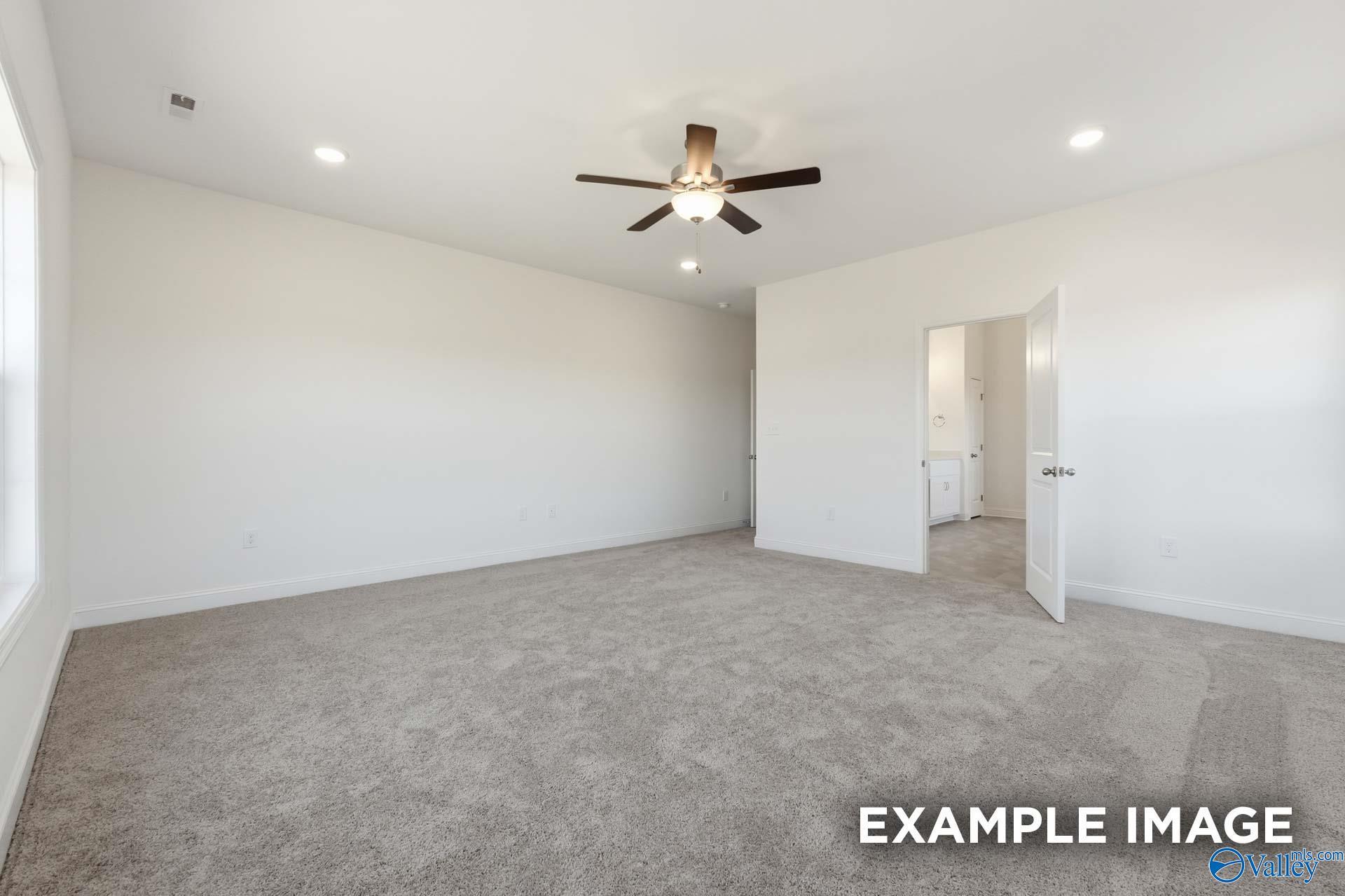 Spacious bedroom with ceiling fan and attached bathroom in The Valencia floor plan by Davidson Homes in Briercreek.