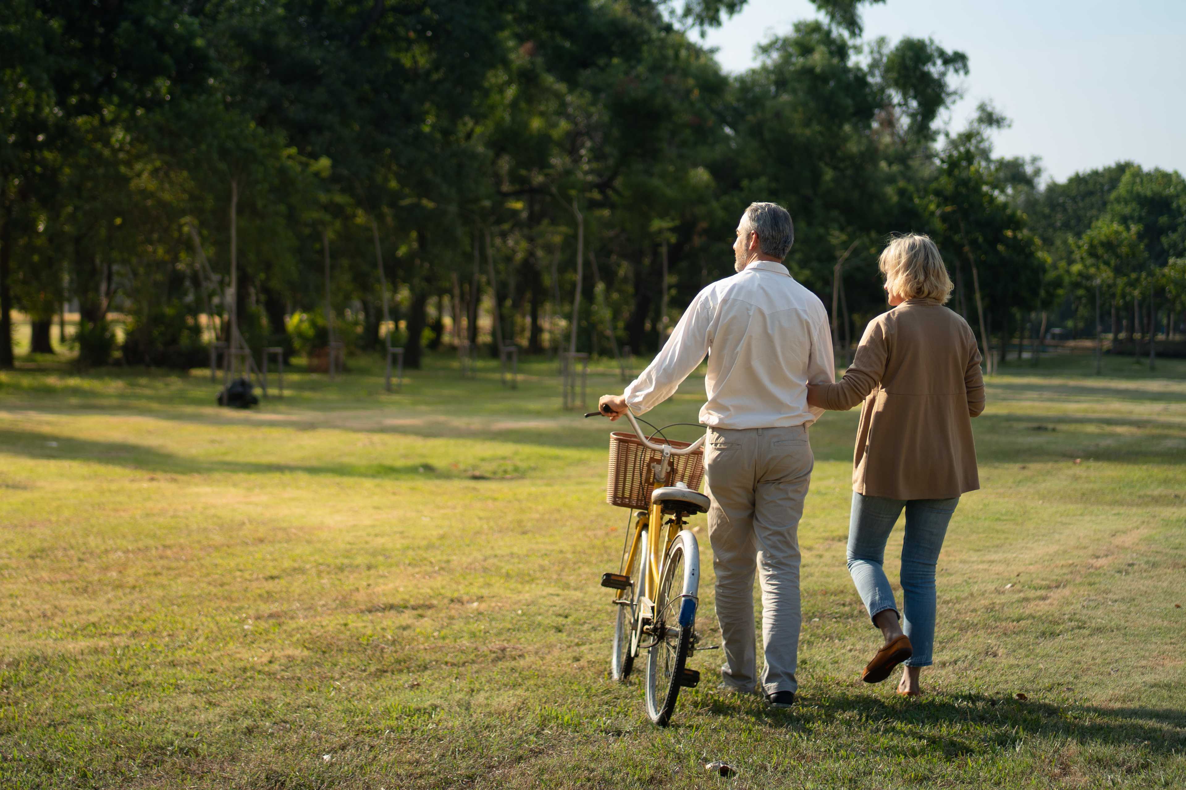 Senior couple strolling hand-in-hand with yellow bicycle through wooded park at Kelly Preserve, Loganville GA