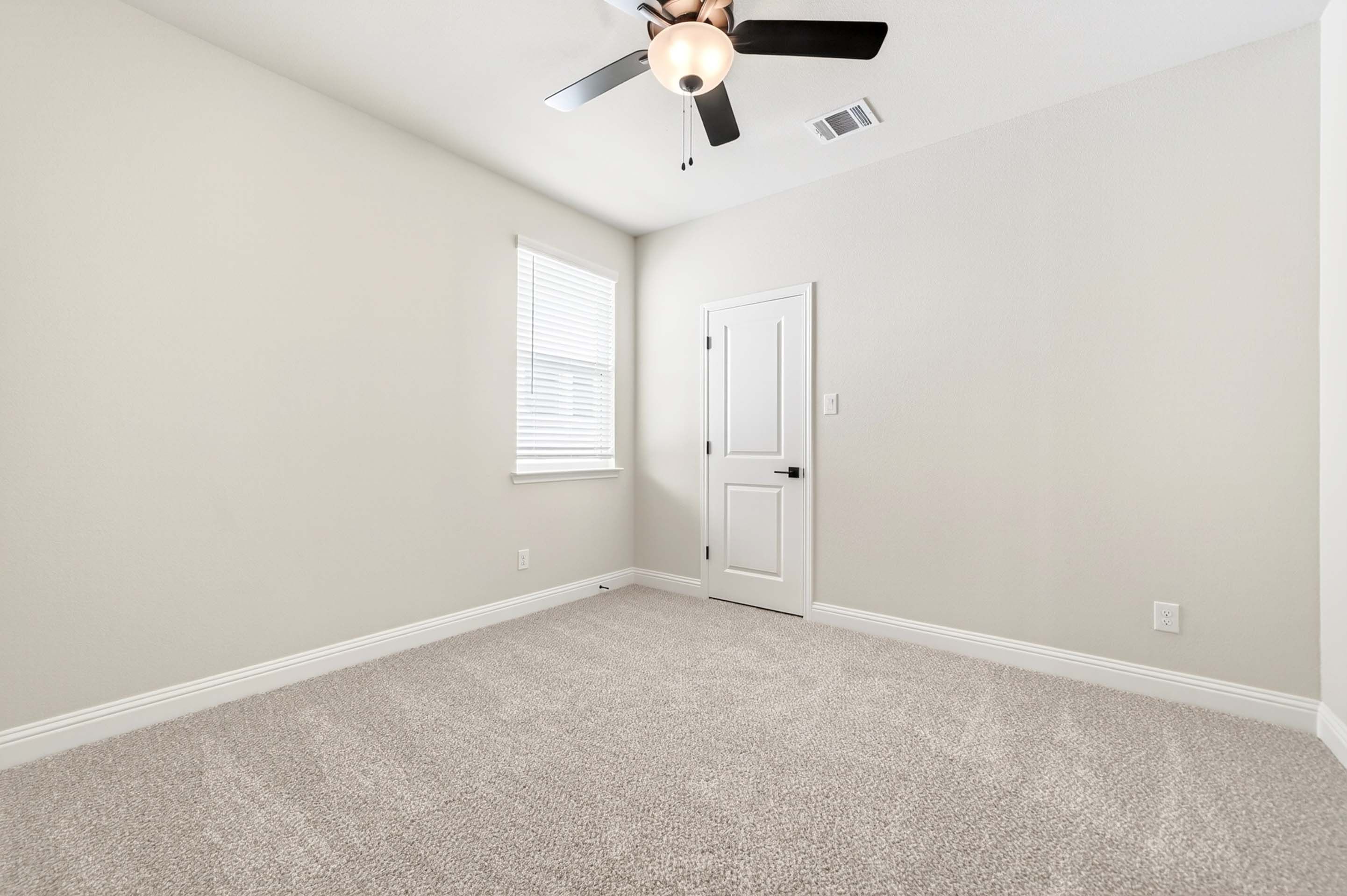 Spacious secondary bedroom in The Holly floor plan featuring neutral carpet, white walls, and a ceiling fan.