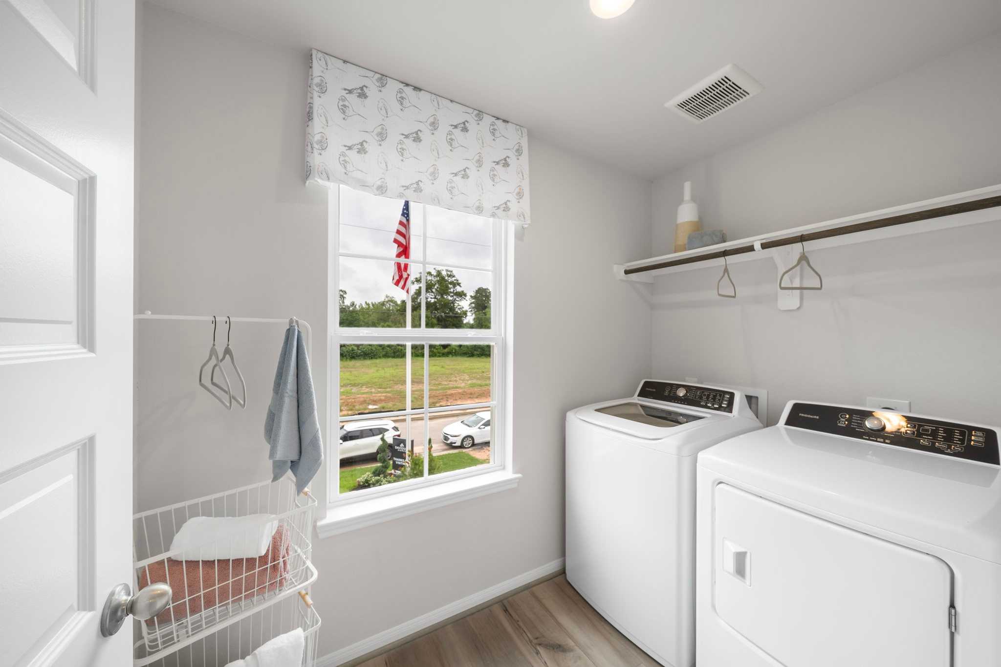 Spacious laundry room at Hill & Dale Ranch in Splendora Texas with white washer dryer built-in shelves and window view