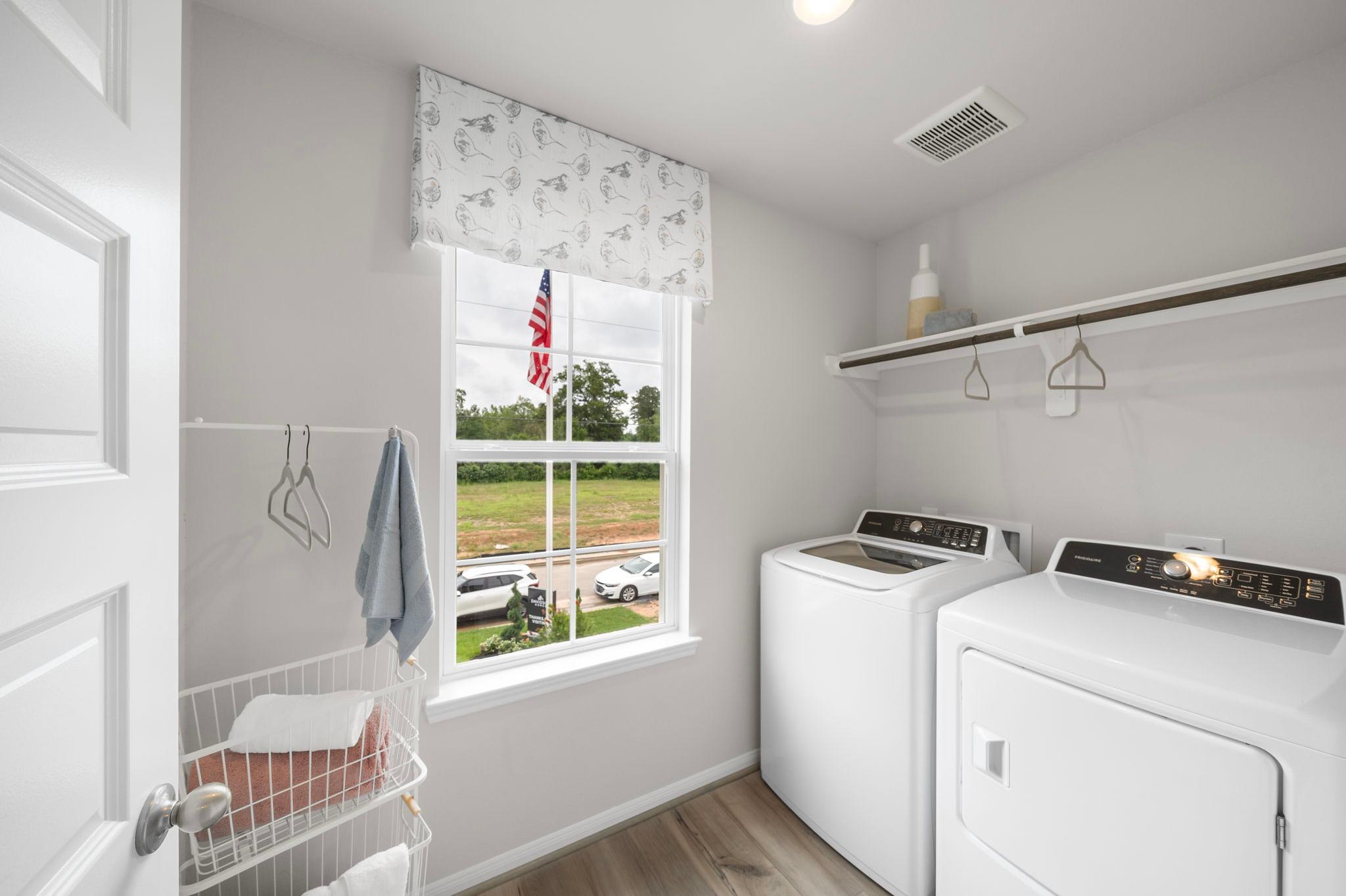 Spacious laundry room at Hill & Dale Ranch in Splendora Texas with white washer dryer built-in shelves and window view