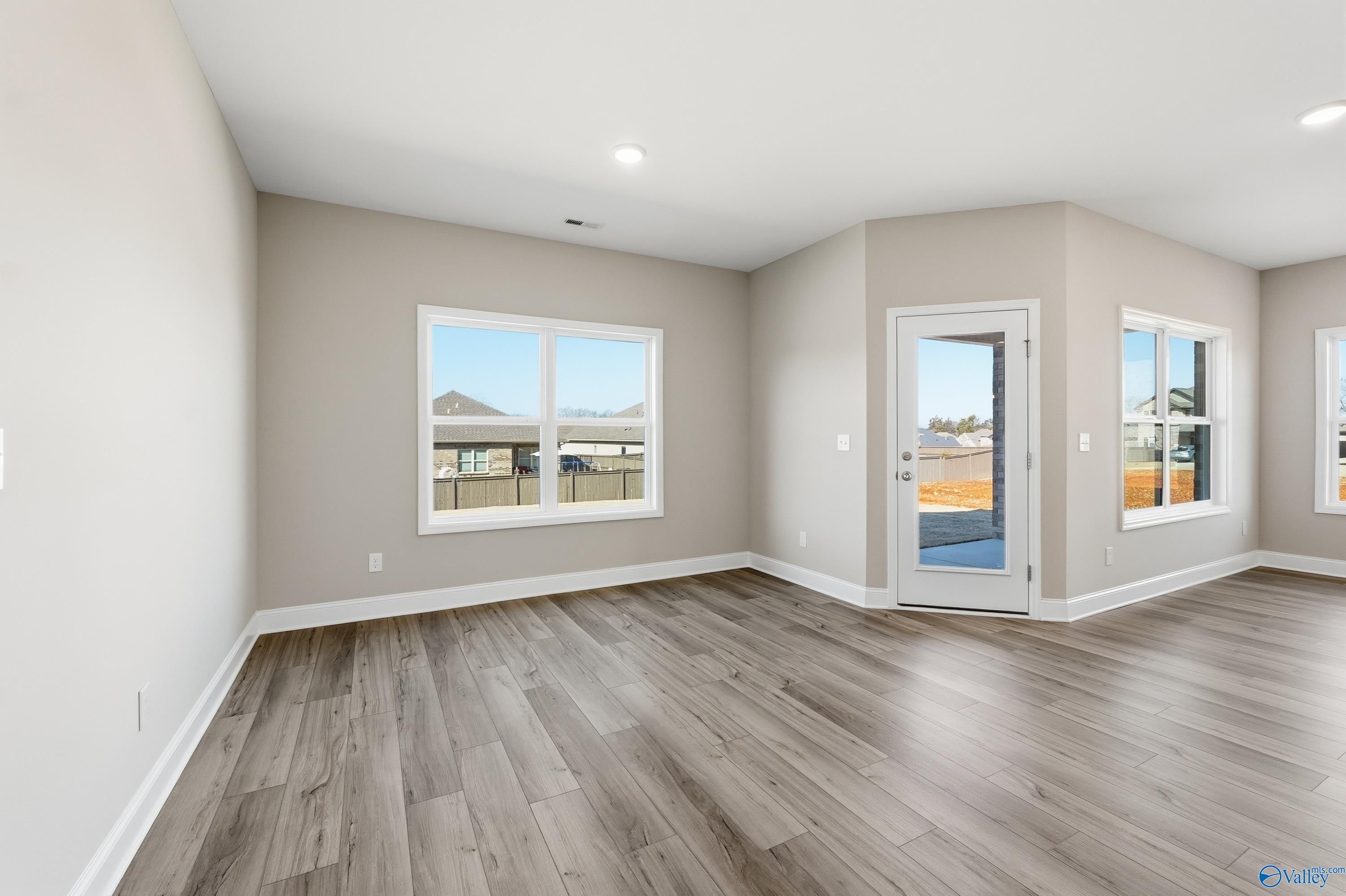 Bright living room with hardwood floors, large windows, and glass door in Davidson Homes The Franklin C, New Market, Alabama