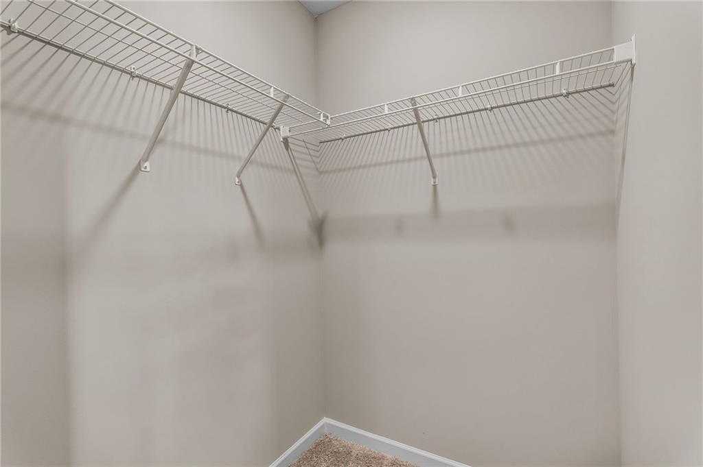 Spacious corner walk-in closet with wire shelving on beige walls in Davidson Homes The Bartlett, Phenix City, Alabama
