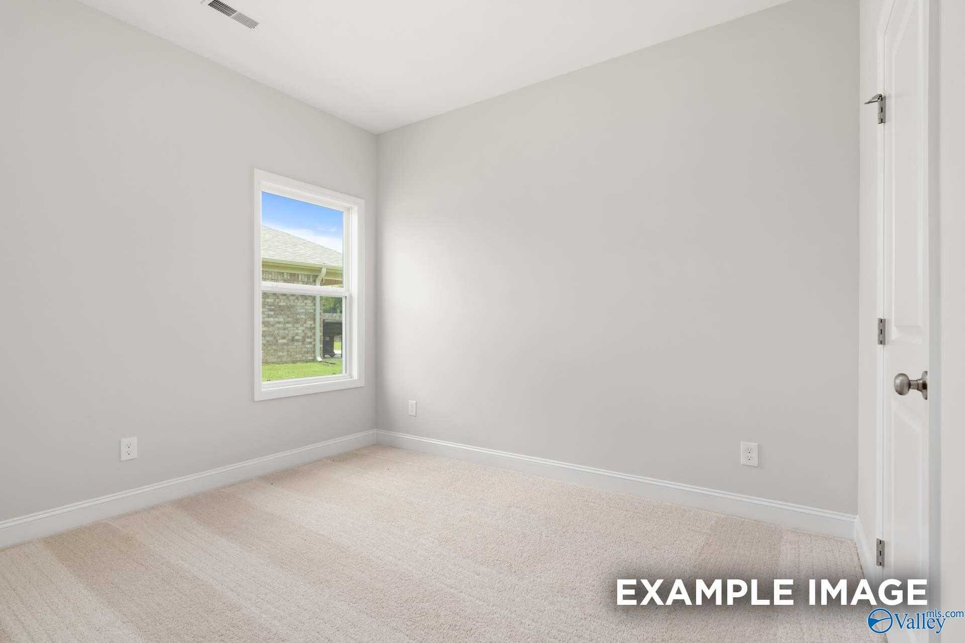 Bright secondary bedroom with light gray walls, large window to green lawn, beige carpet in Davidson Homes The Asheville C, Meridianville, Alabama