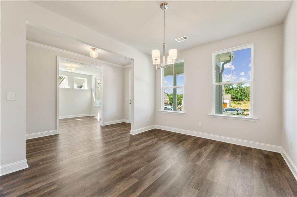 Elegant dining room with hardwood floors, chandelier, and large windows overlooking backyard in The Danbury E, Buford, Georgia