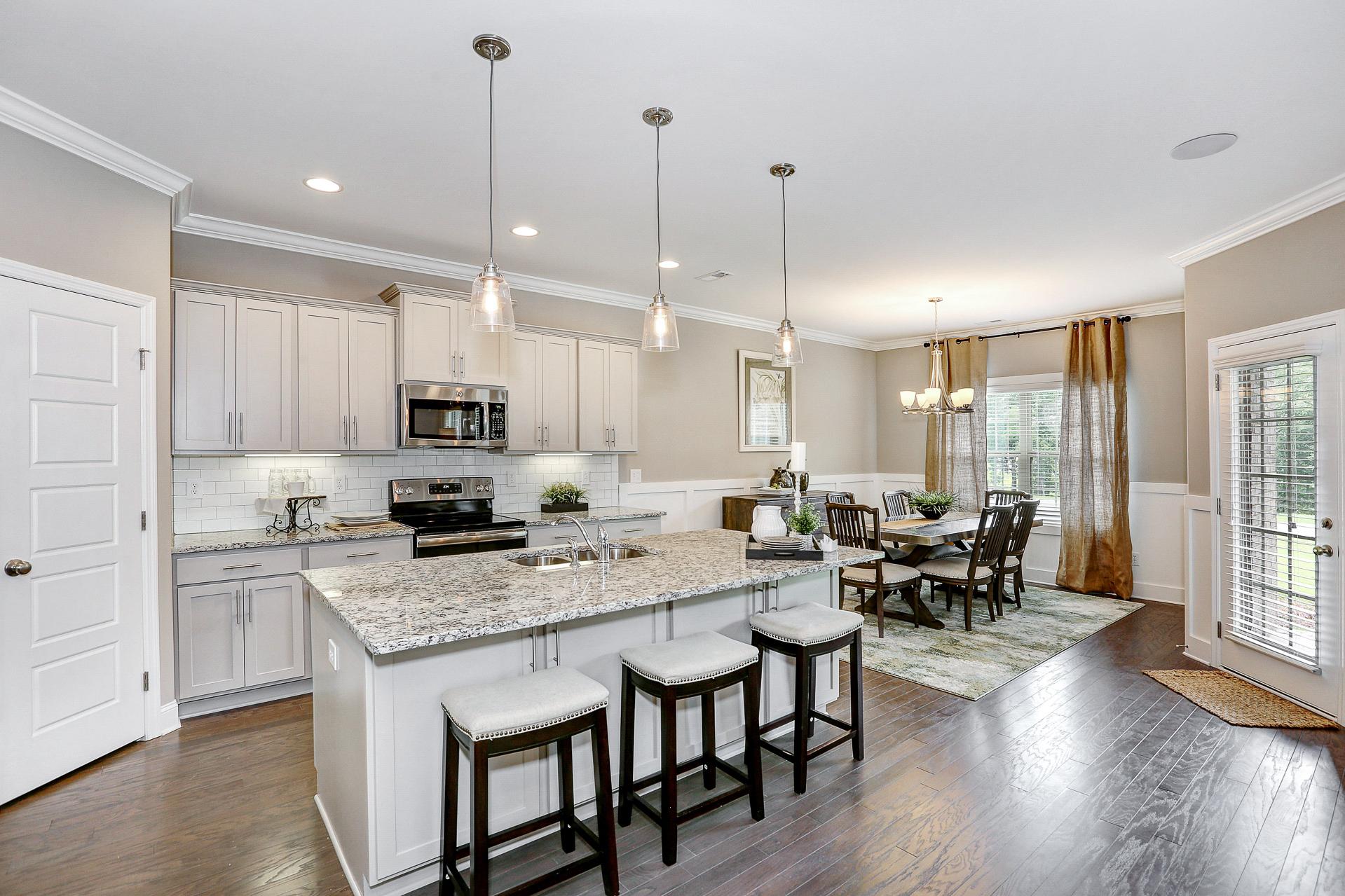 Spacious open-concept kitchen dining area Stone Creek Phase II Cullman AL white shaker cabinets granite island hardwood floors pendant lights
