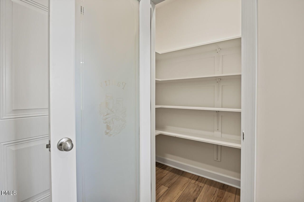 Walk-in pantry with frosted glass door and white shelving in Davidson Homes Hickory II B, Lillington, North Carolina