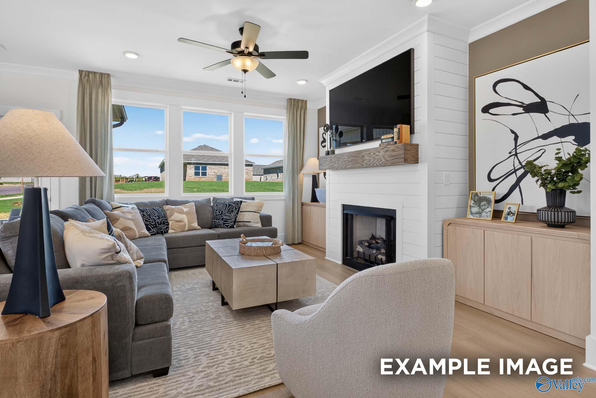 Bright great room with gray sectional, fireplace, and mounted TV in Davidson Homes The Ashport K, Forest Glen, Hazel Green, Alabama
