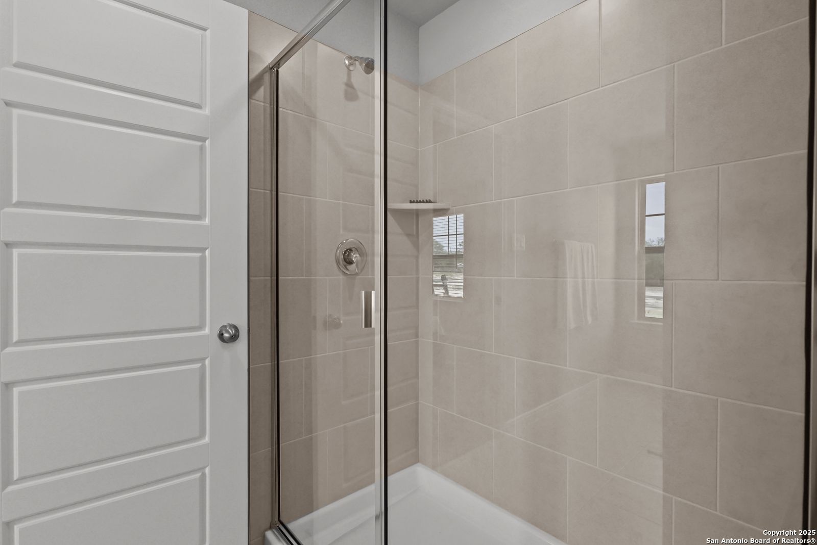 Elegant bathroom with glass shower enclosure, beige tiles, and tub in Davidson Homes The Gillian C, San Antonio, Texas