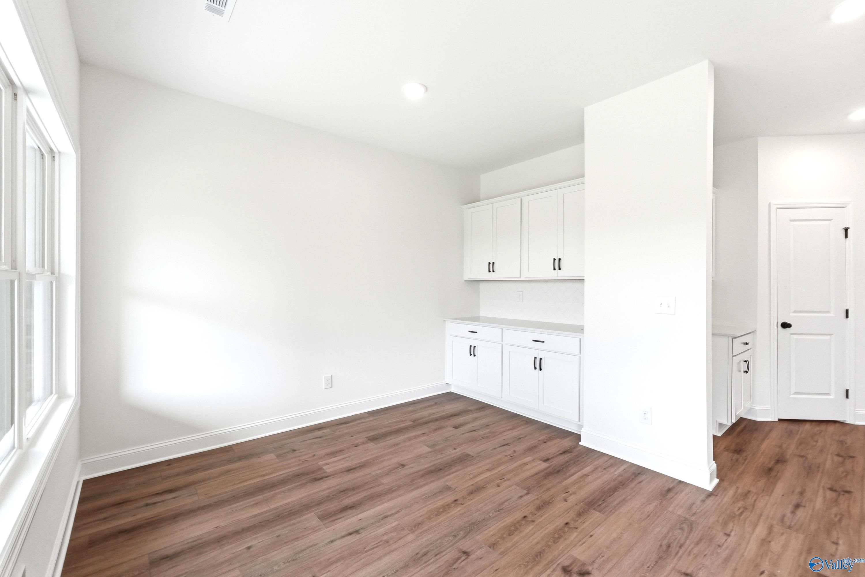 Dining area with white cabinetry and wood-look flooring in The Daphne C floor plan by Davidson Homes in Ivy Hills, Toney.
