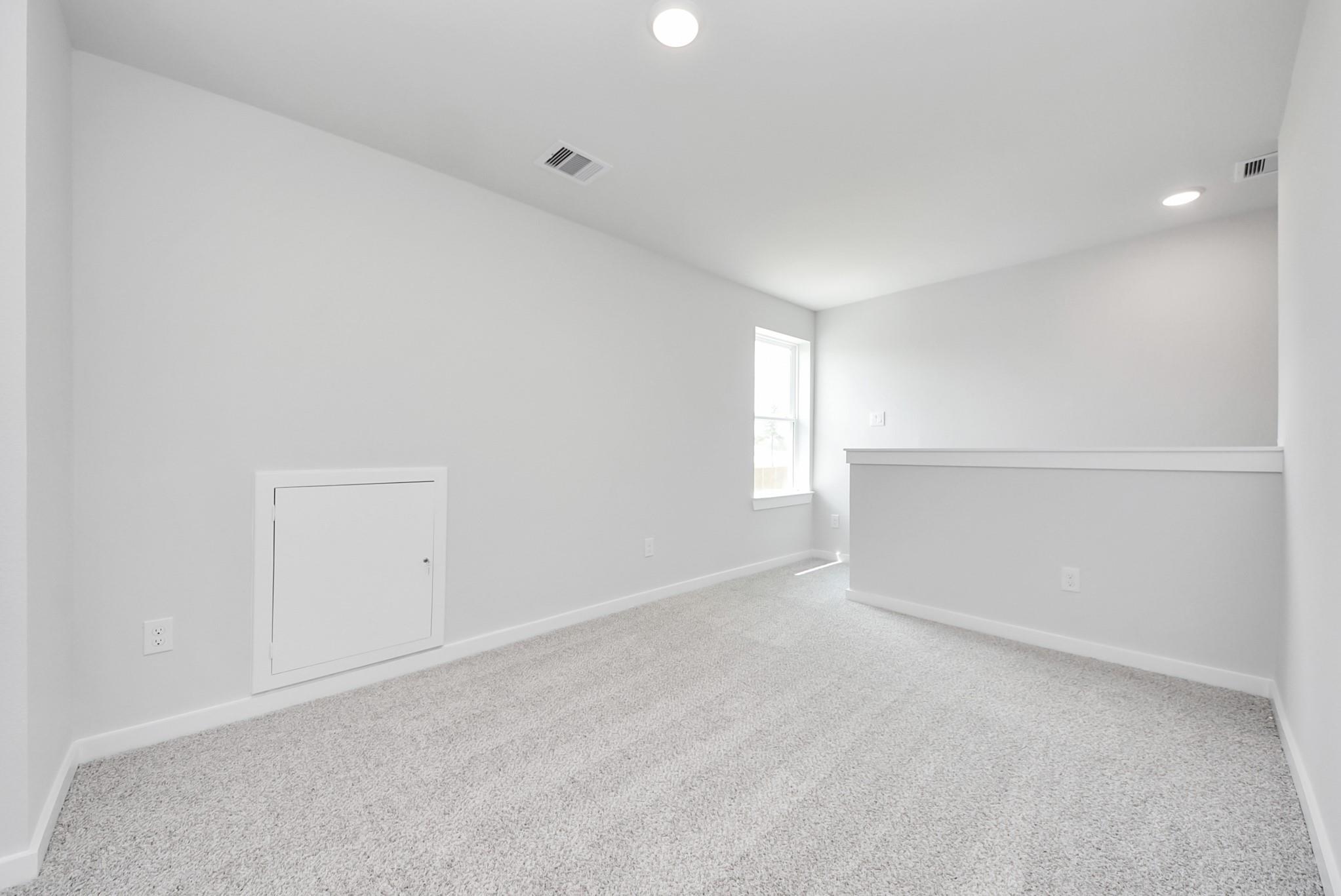 Spacious carpeted game room in The Blanco F floor plan at Spring Branch Crossing, Conroe, Texas.