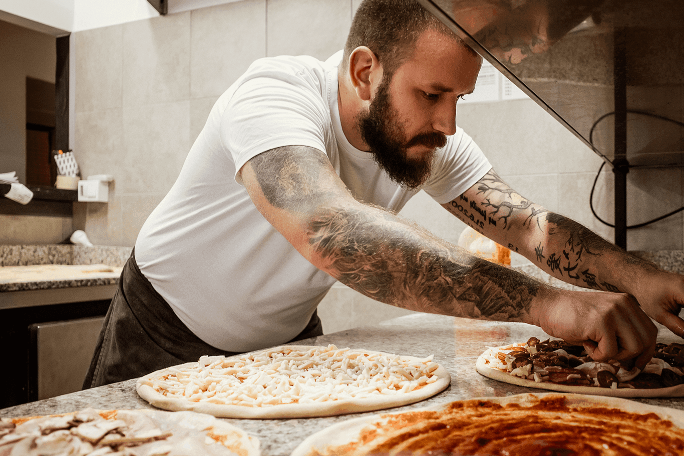 Restaurant employee adding toppings to pizzas - restaurant POS system - SkyTab
