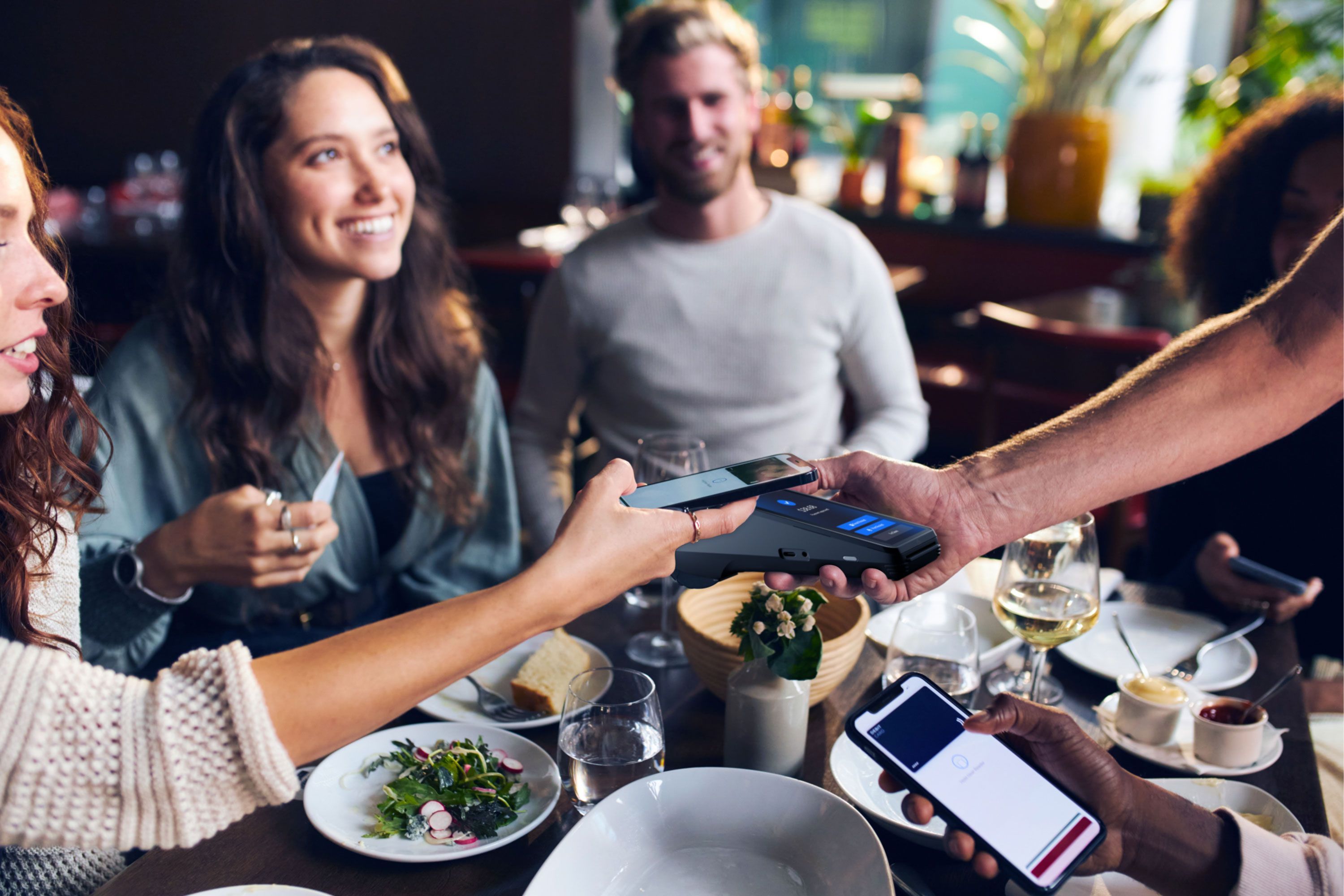 Restaurant server presenting a SkyTab mobile POS device at a table and a customer tapping their phone to pay - mobile POS system - SkyTab