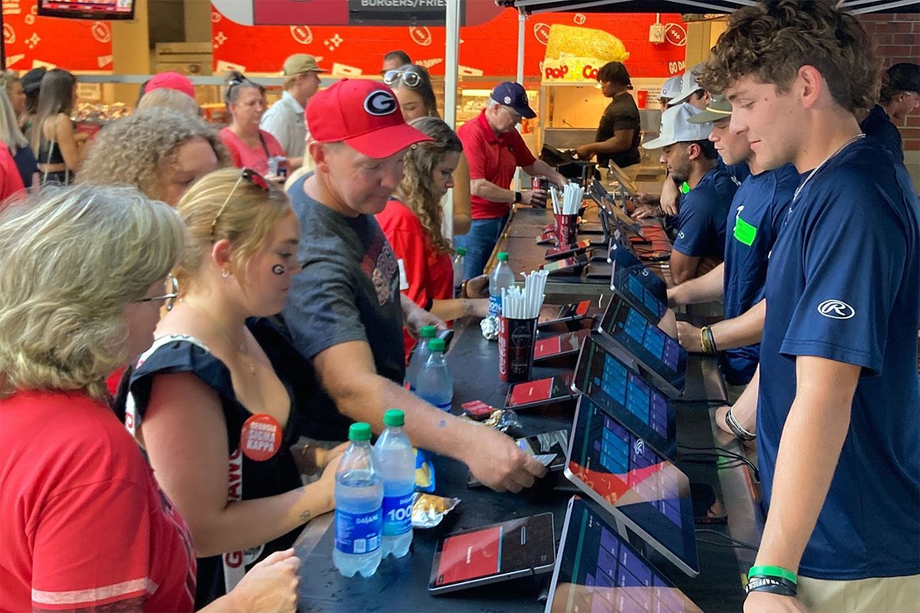 Concession stand at a large football venue showing customers buying food and beverages - venue POS system - Shift4
