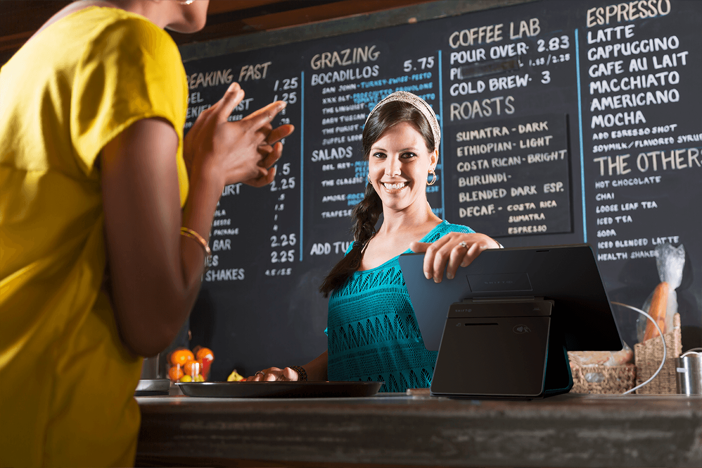 Restaurant employee standing behind a Shift4 Dine POS system while serving a customer - restaurant POS system - Shift4 Dine