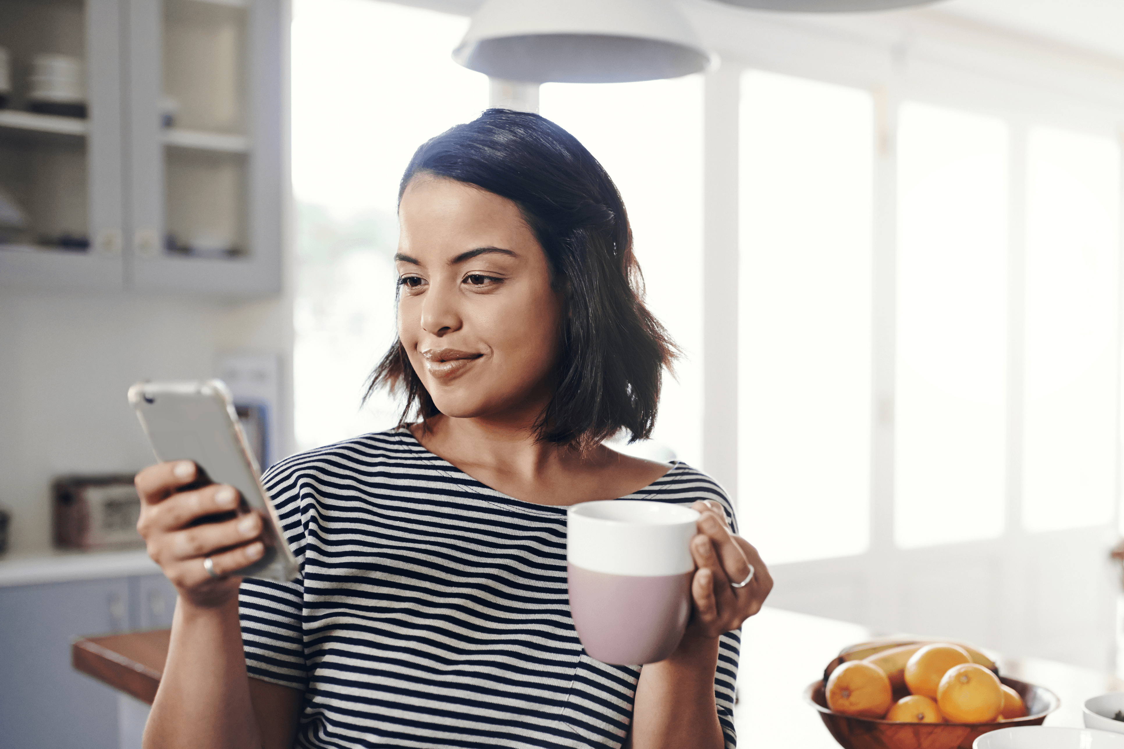 Woman holding a coffee cup looking at her smartphone - restaurant labor management - Shift4 Dine