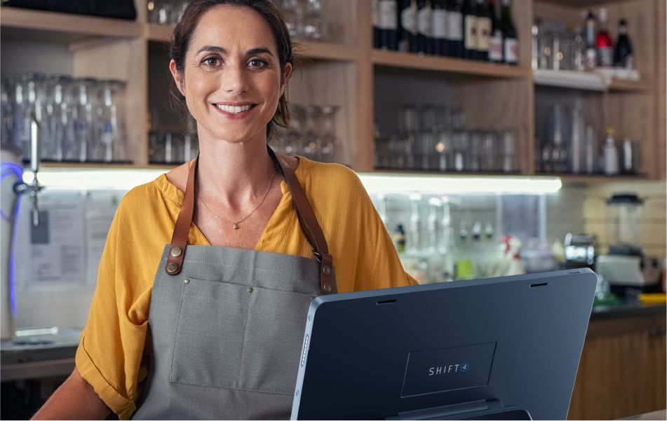 Smiling restaurant employee standing behind a SkyTab POS system - Referral Program - SkyTab