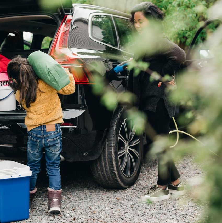 En familie, der pakker ting ind i en elbil udendørs.