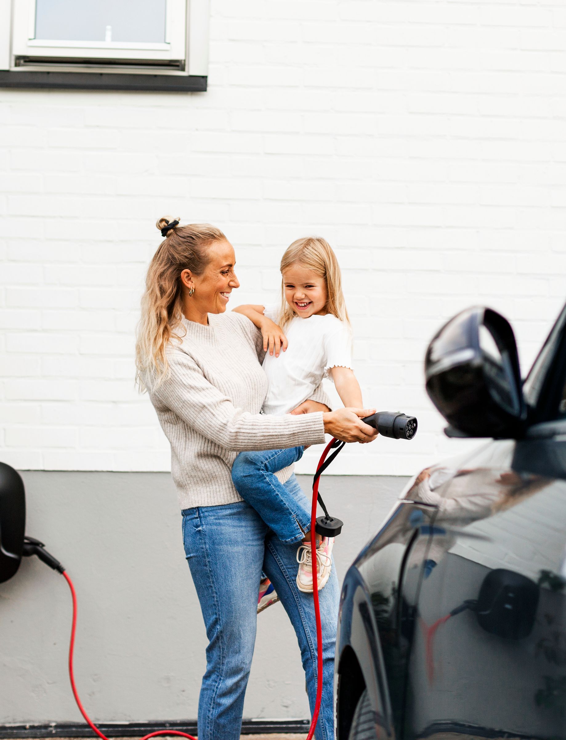 En familie, der pakker ting ind i en elbil udendørs.