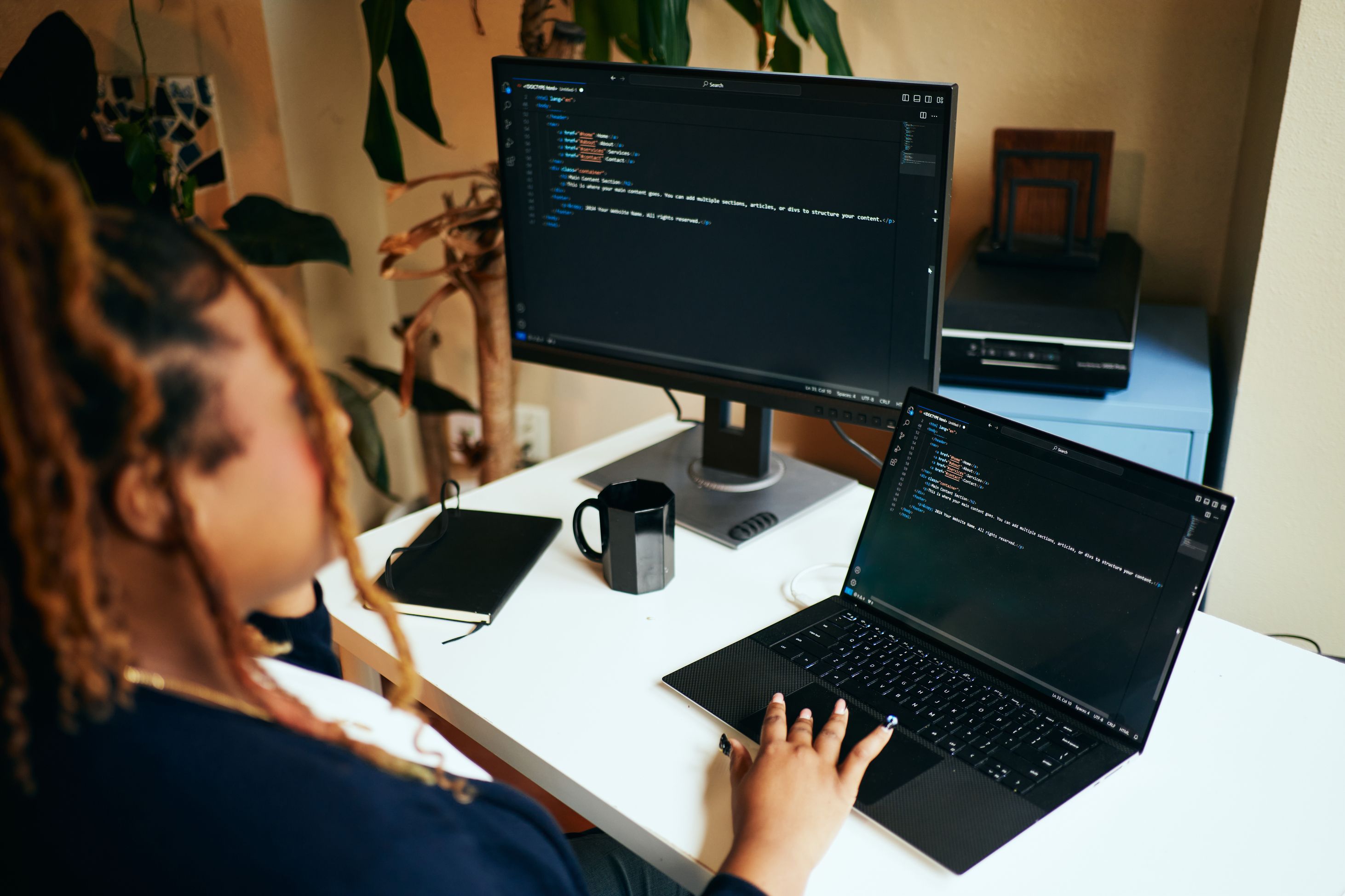 Woman coding on a laptop with external monitor