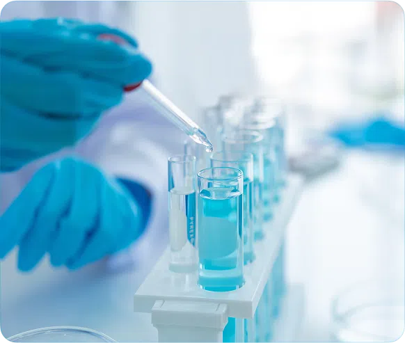 Hands in gloves using dropper to fill test tubes