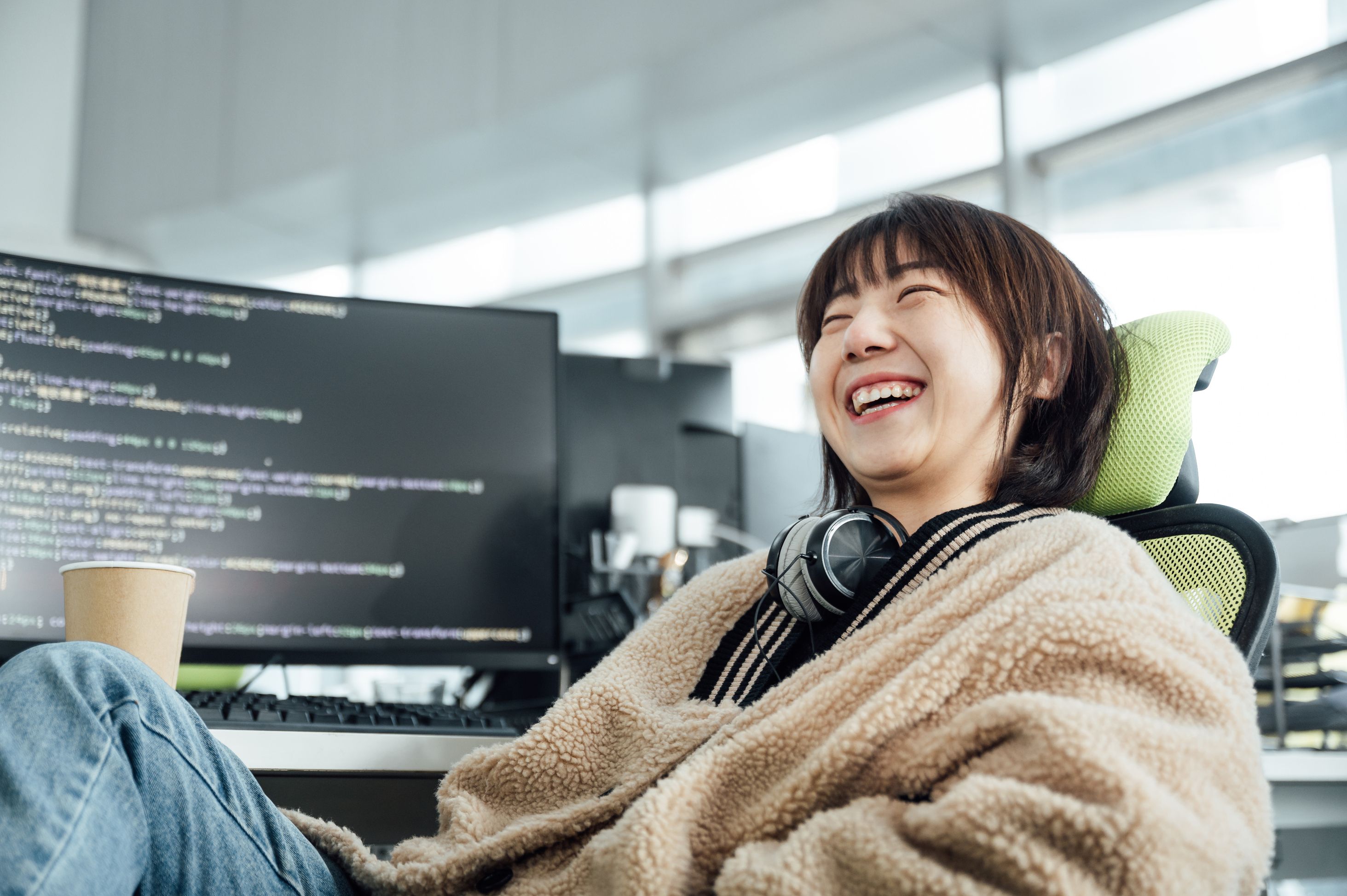 Woman writing code at a desk and smiling