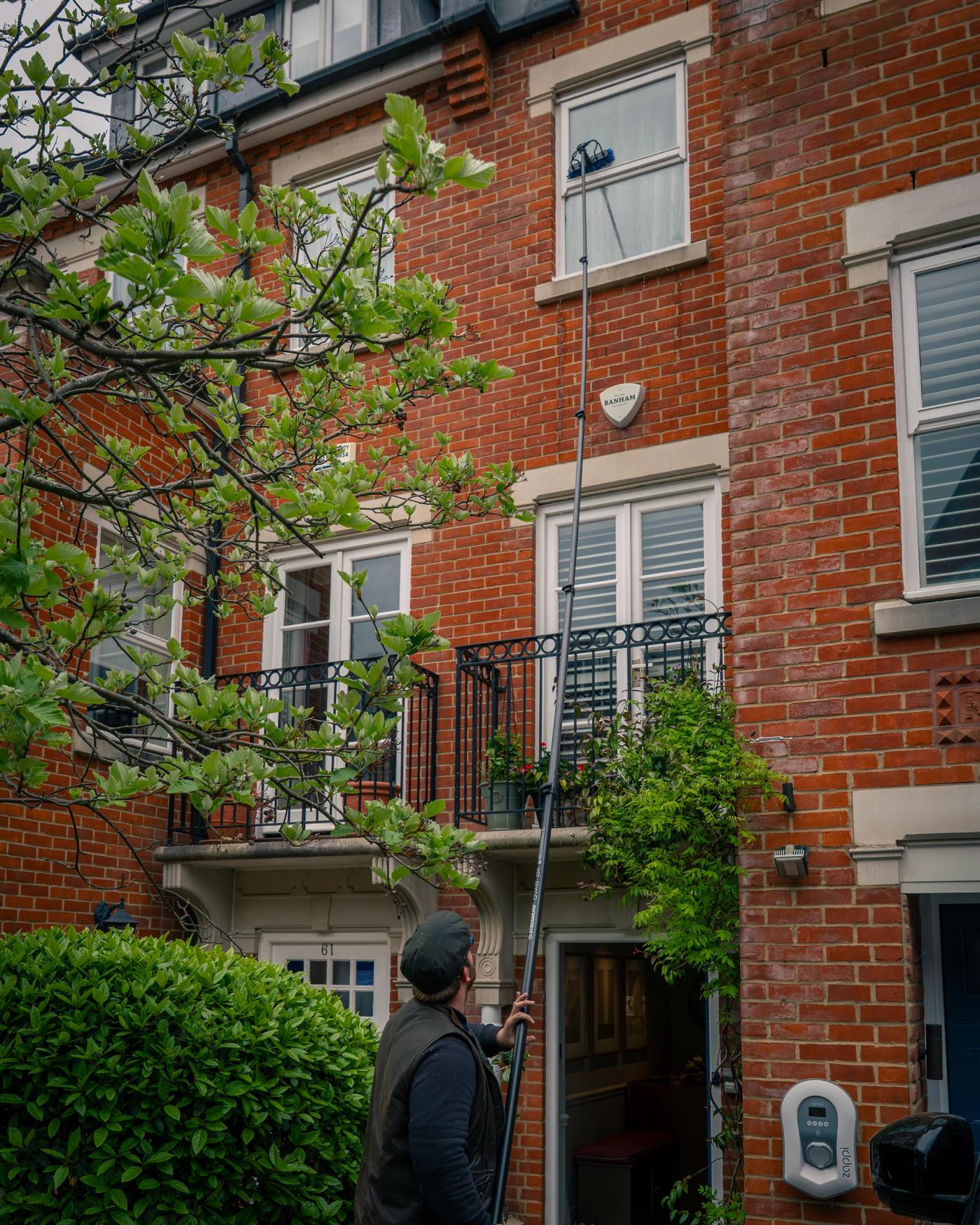 A managed period commercial property with tall cleaned windows, clear entrance glazing, stone details and a discreet professional cleaning setup