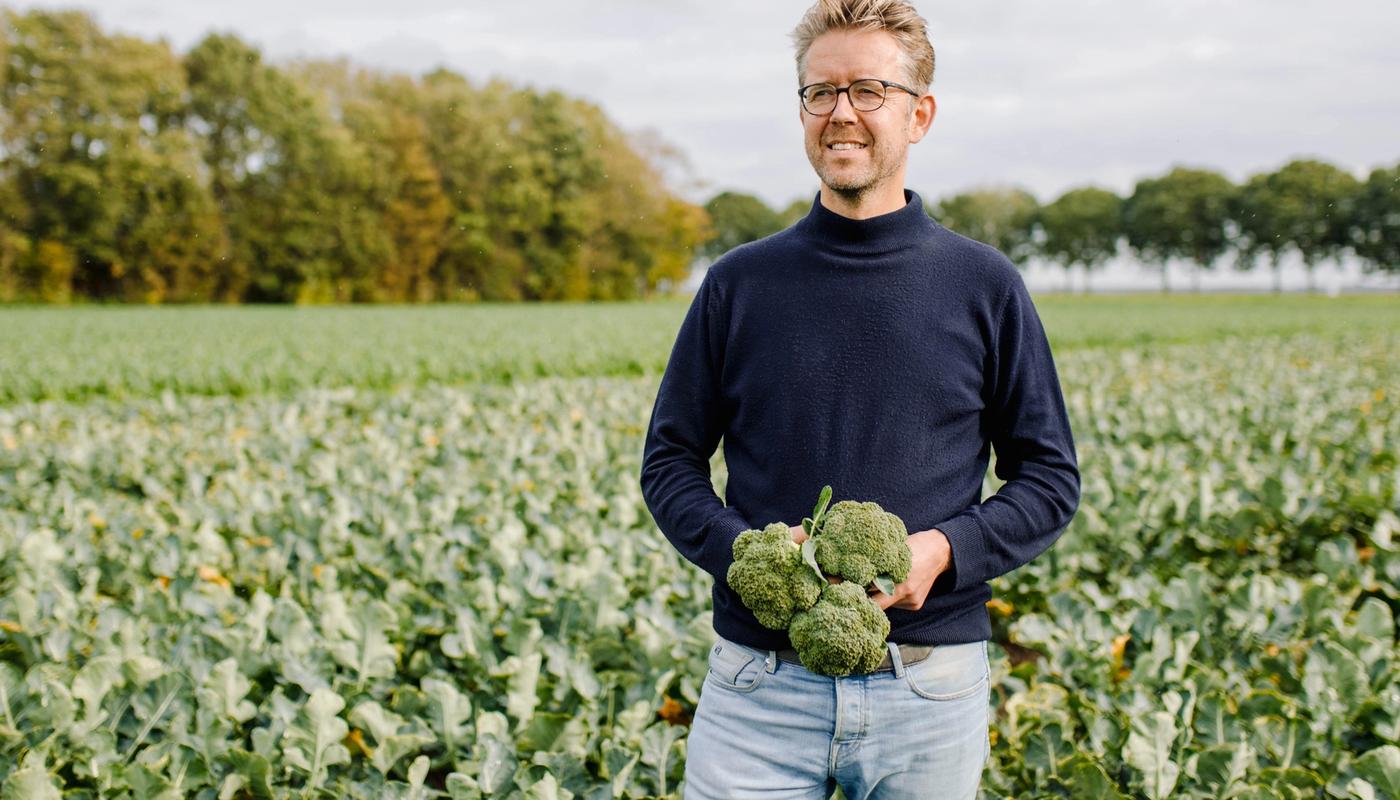 Boer Gerjan Snippe staat in de polder met broccoli in zijn hand.
