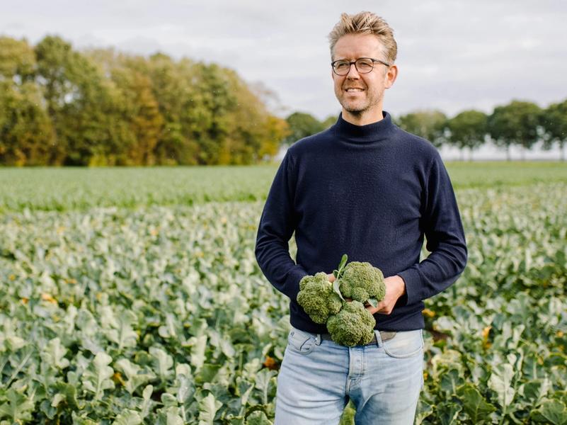 Boer Gerjan Snippe staat in de polder met broccoli in zijn hand.