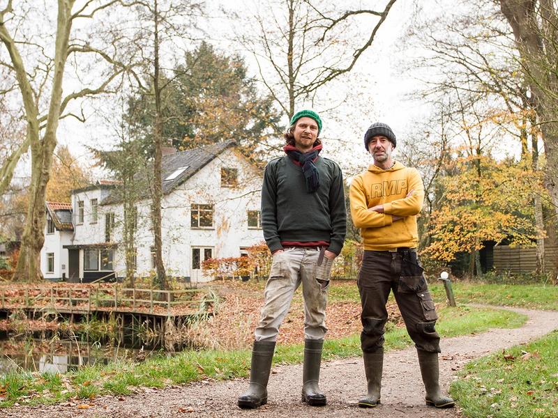 Tuinders Jasper en Dave staan op het pad voor de vijver en het witte koetshuis op Landgoed Kraaybeekerhof.