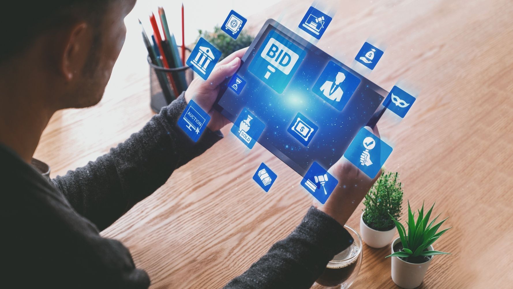 person holding ipad with digital icons like "bid" and a gavel