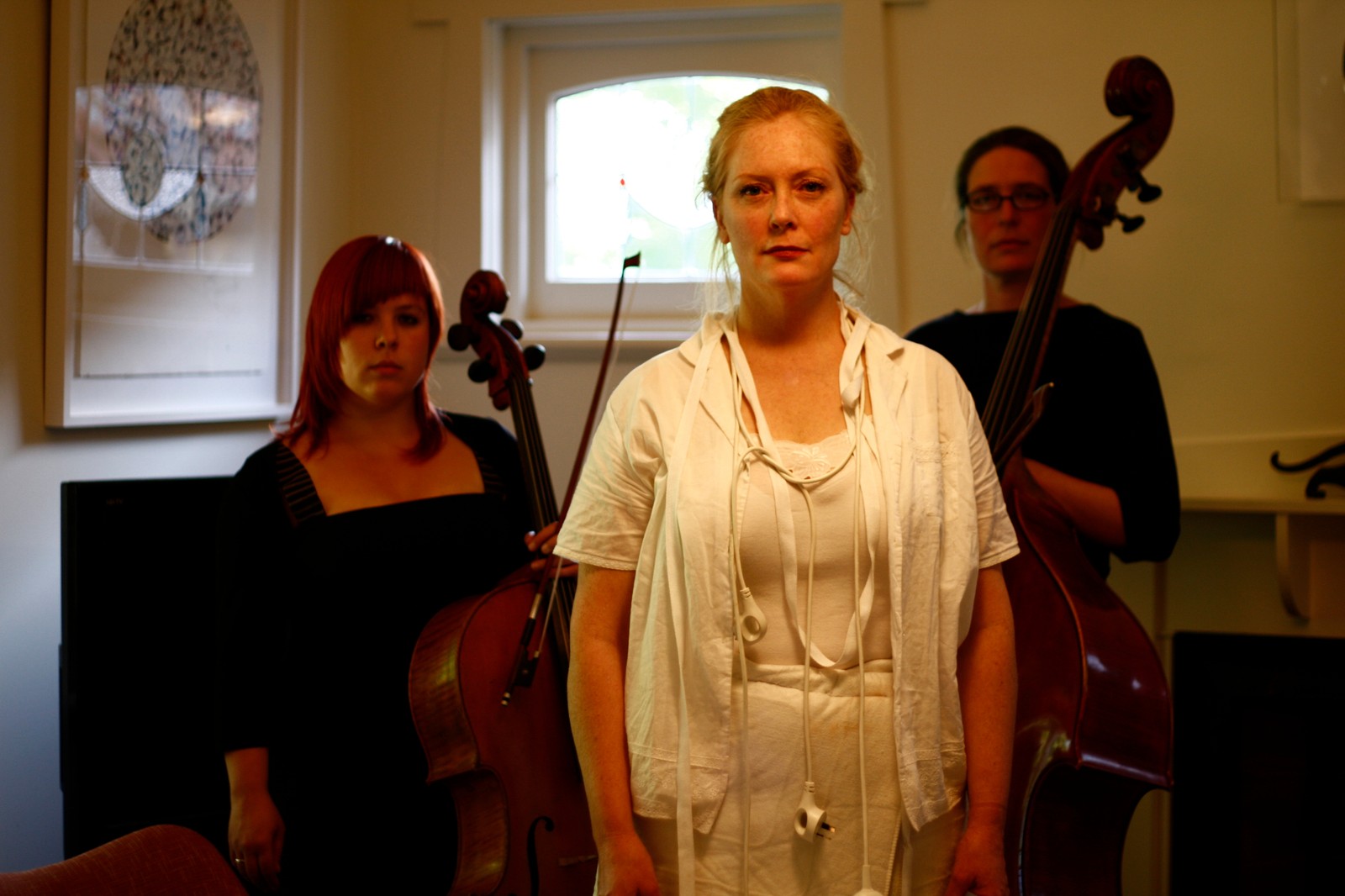 A woman in white stands with a cellist and double bass player as part of The Itch by Chamber Made