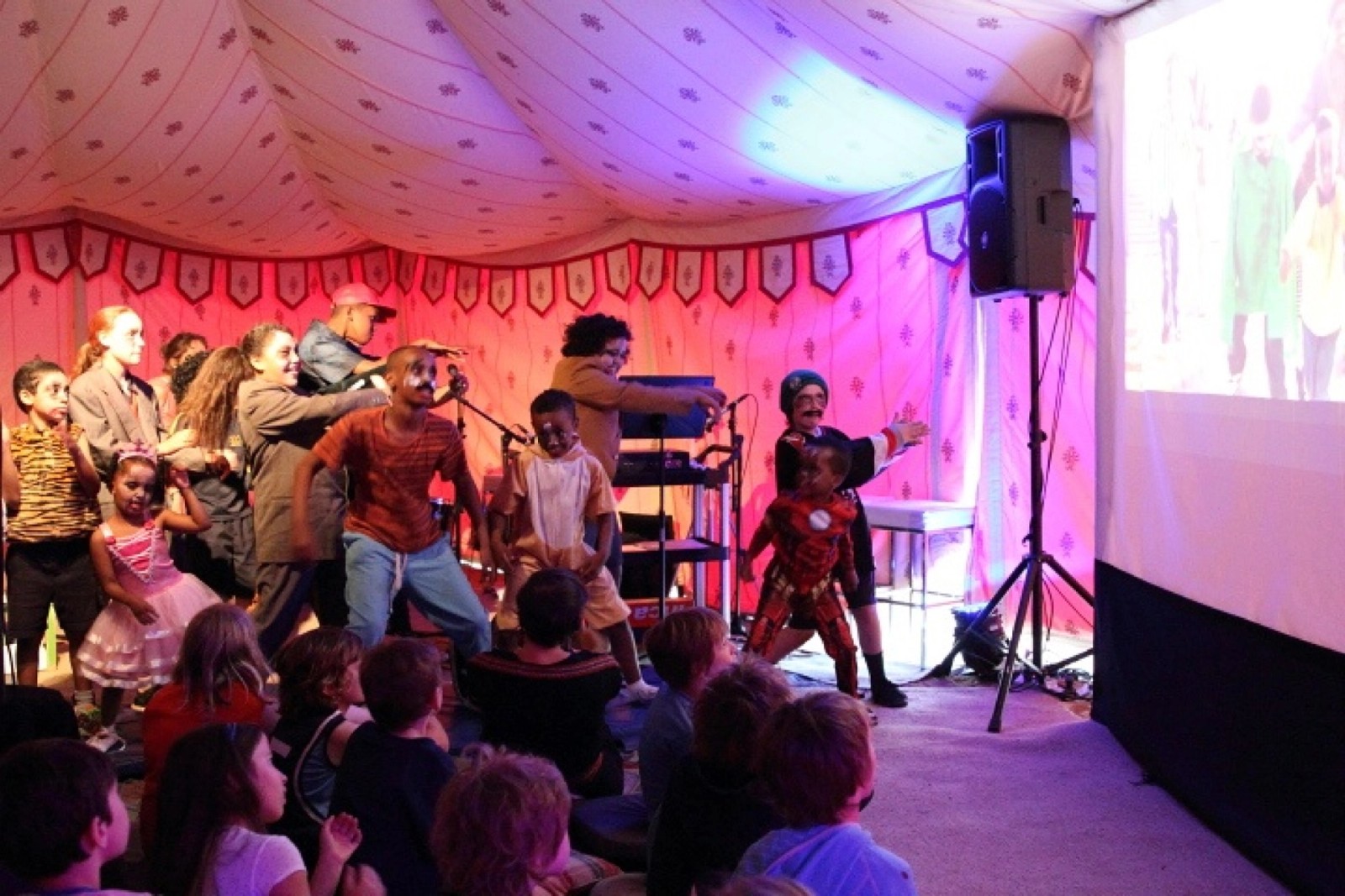 A group of children perform in front of a screen while others watch on as part of Chamber Made's The Venny Project 2012-2014
