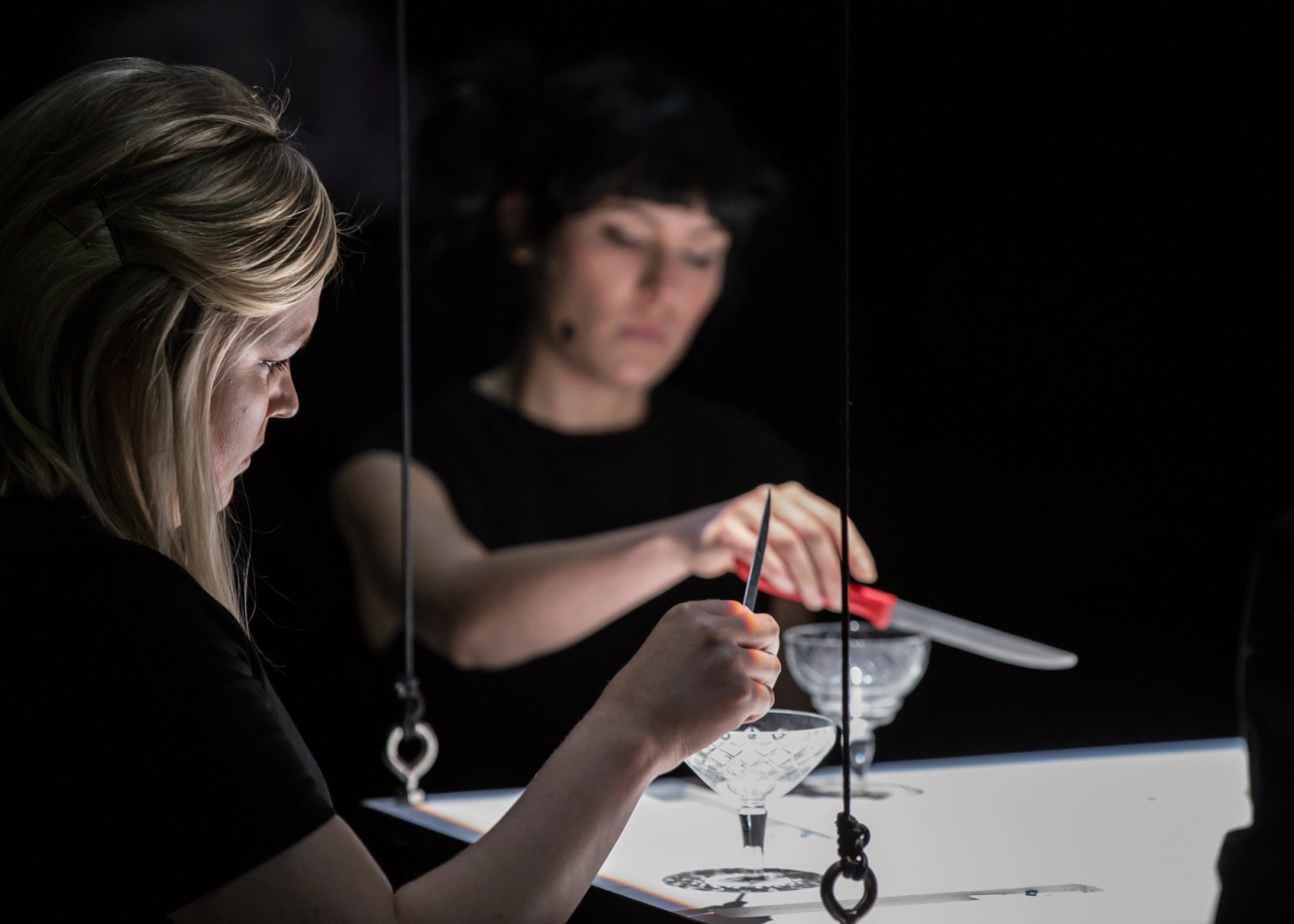Close up of two performers strumming glasses with knives as part of Permission to Speak by Chamber Made