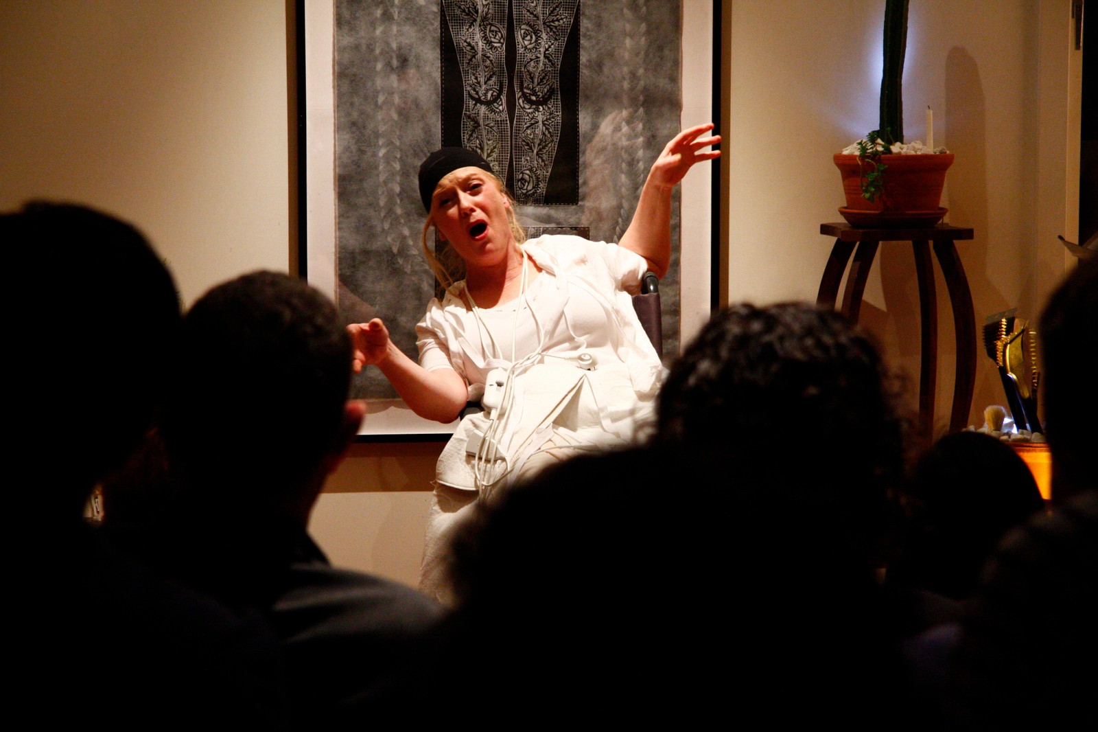 A woman with raised arms performing to a seated audience as part of The Itch by Chamber Made