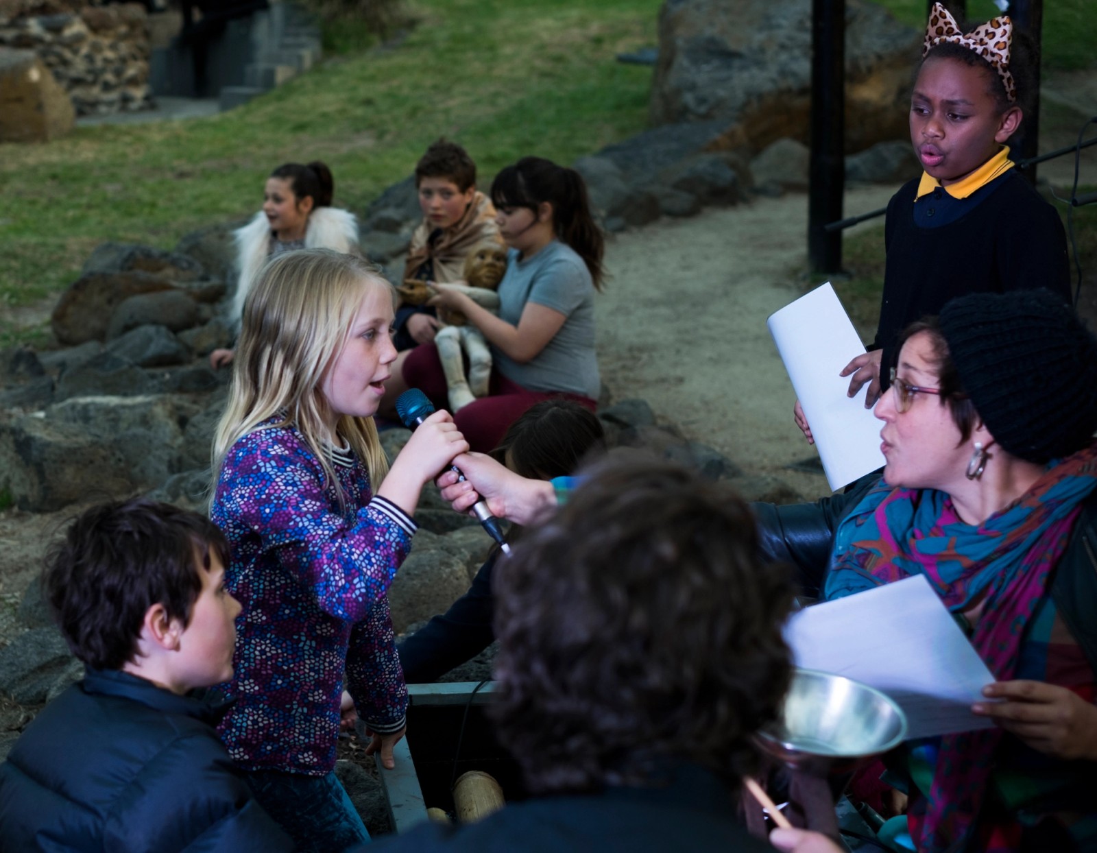 A woman holds a microphone for a girl as others watch on as part of Chamber Made's The Venny Imagine a Place 2017