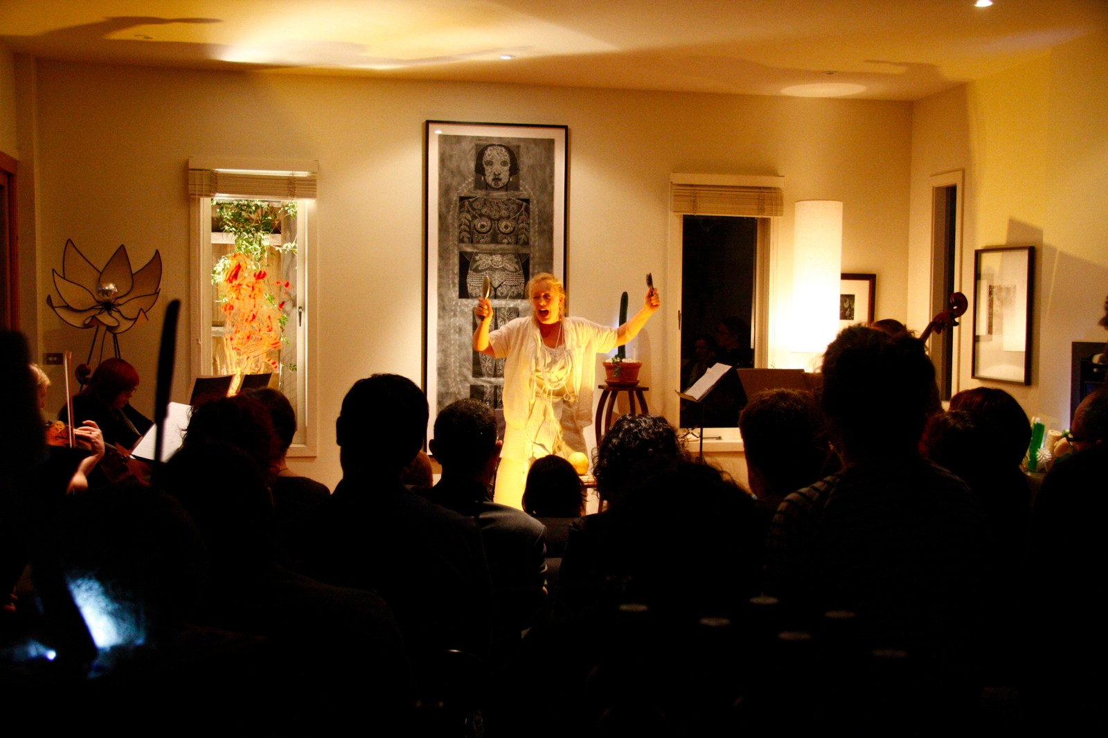 A woman with raised arms performing to a seated audience as part of The Itch by Chamber Made
