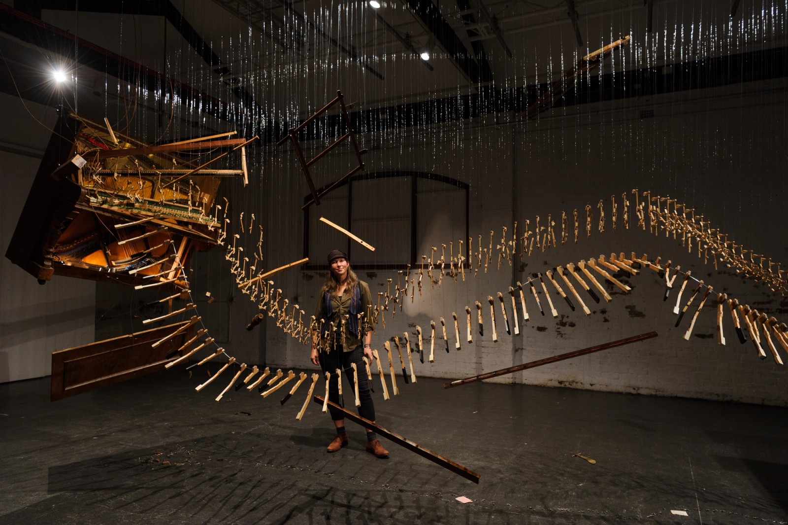 Rae Howell standing in front of a deconstructed and suspended piano