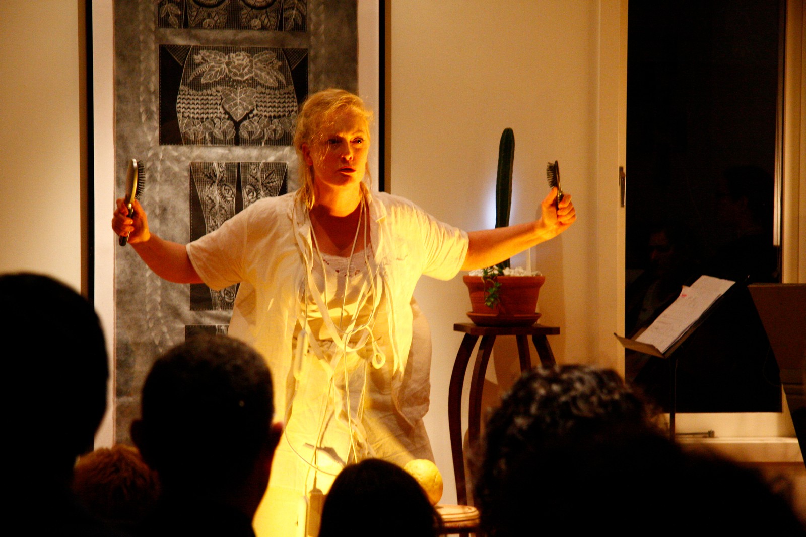 A woman dressed in white with raised arms performing as part of The Itch by Chamber Made
