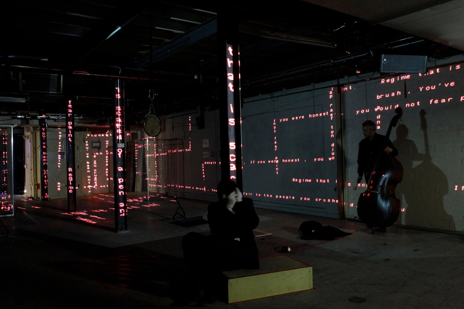 Two performers in a space with projected words as part of Captives of the City by Chamber Made