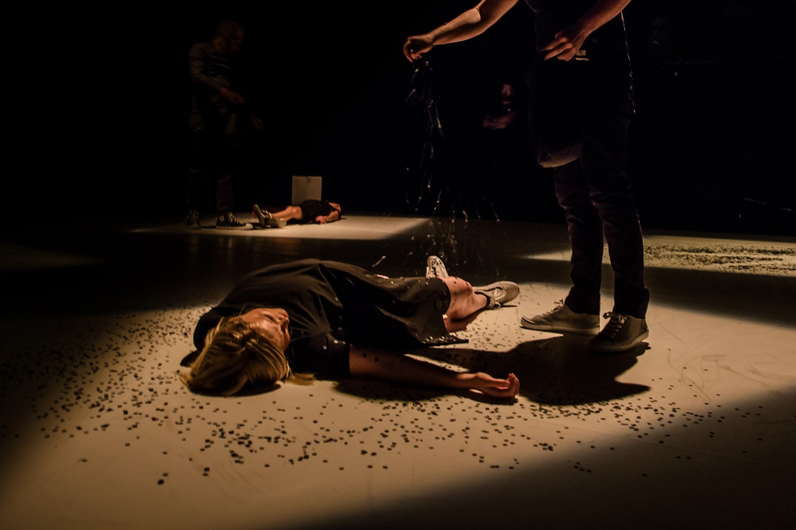 A performer lies on the floor while another scatters confetti on her as part of Permission to Speak by Chamber Made