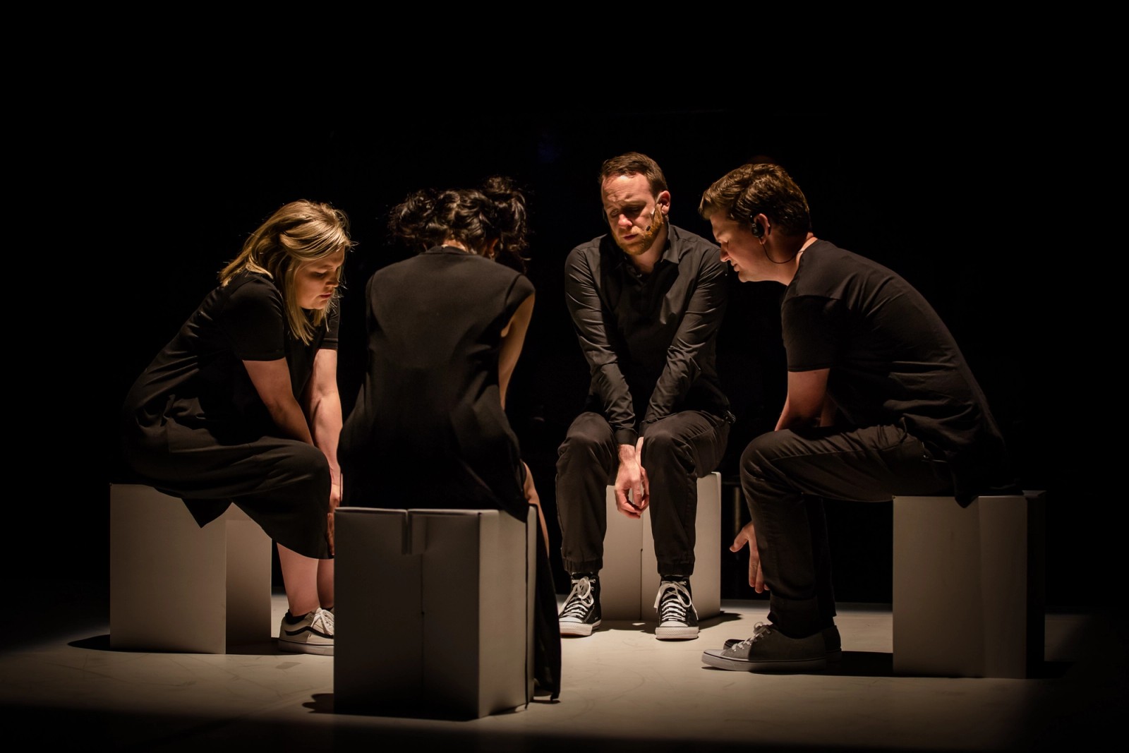 Four performers in a tight circle sitting on white boxes as part of Permission to Speak by Chamber Made