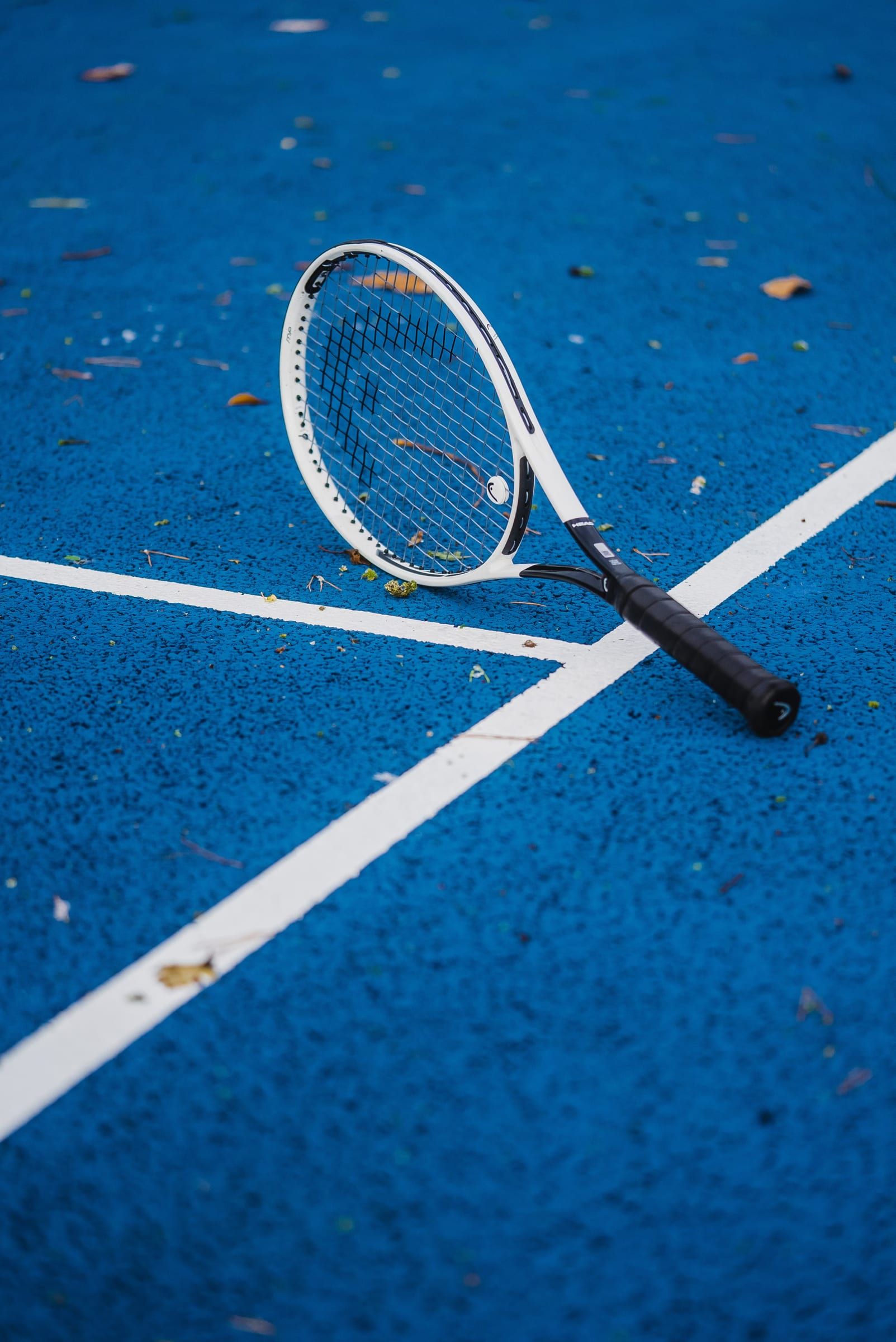 White racket lying across the lines of a blue court