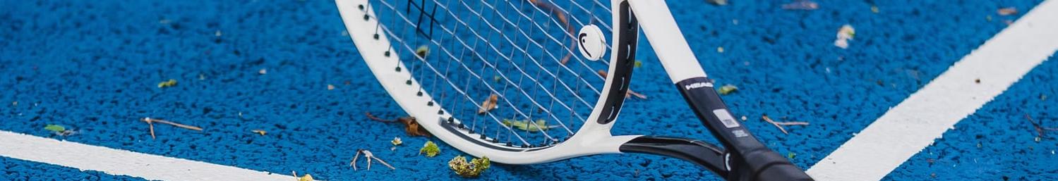 White racket lying across the lines of a blue court